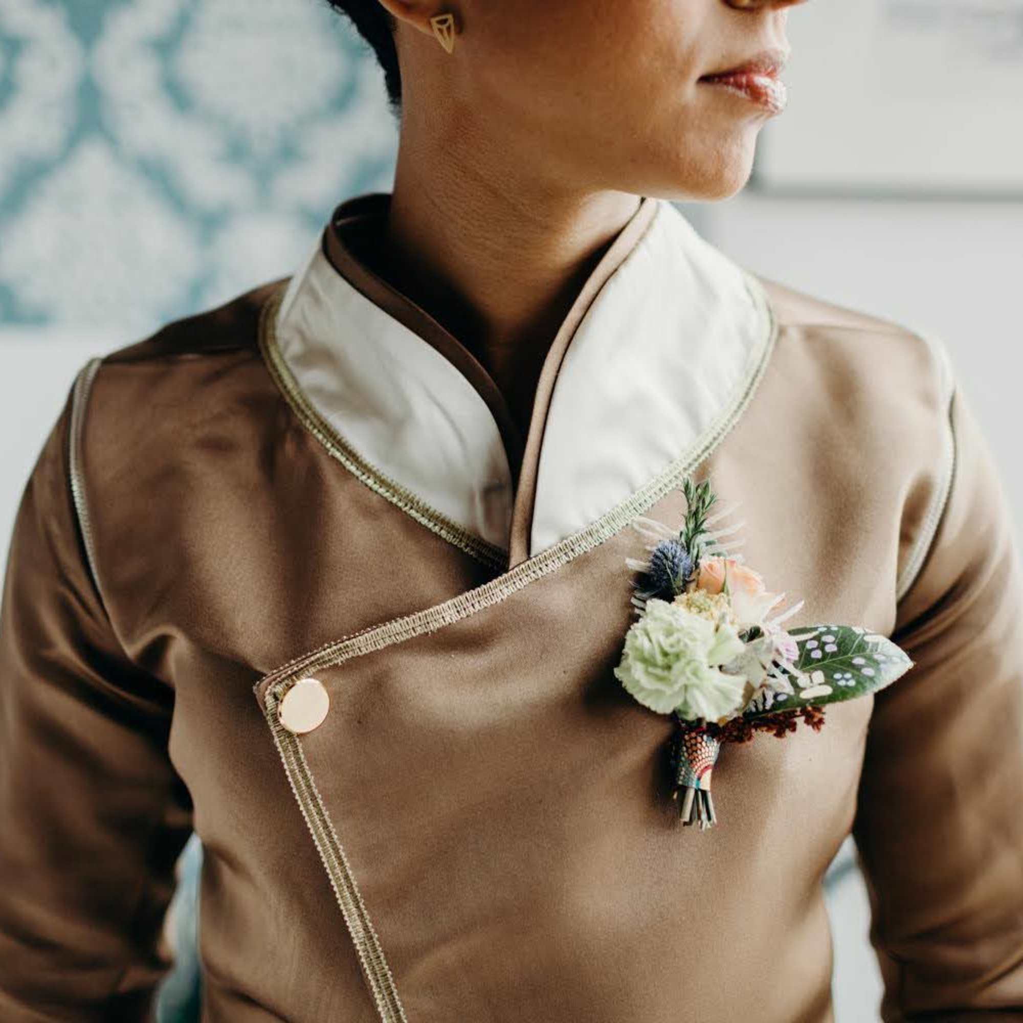 Person wearing a boutonniere on a tan formal jacket
