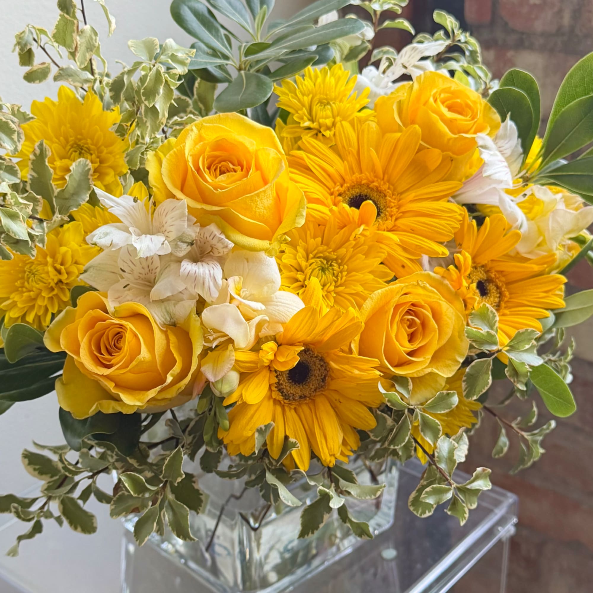 Yellow roses and daisies arranged in a clear glass vase, photo 2 of 2