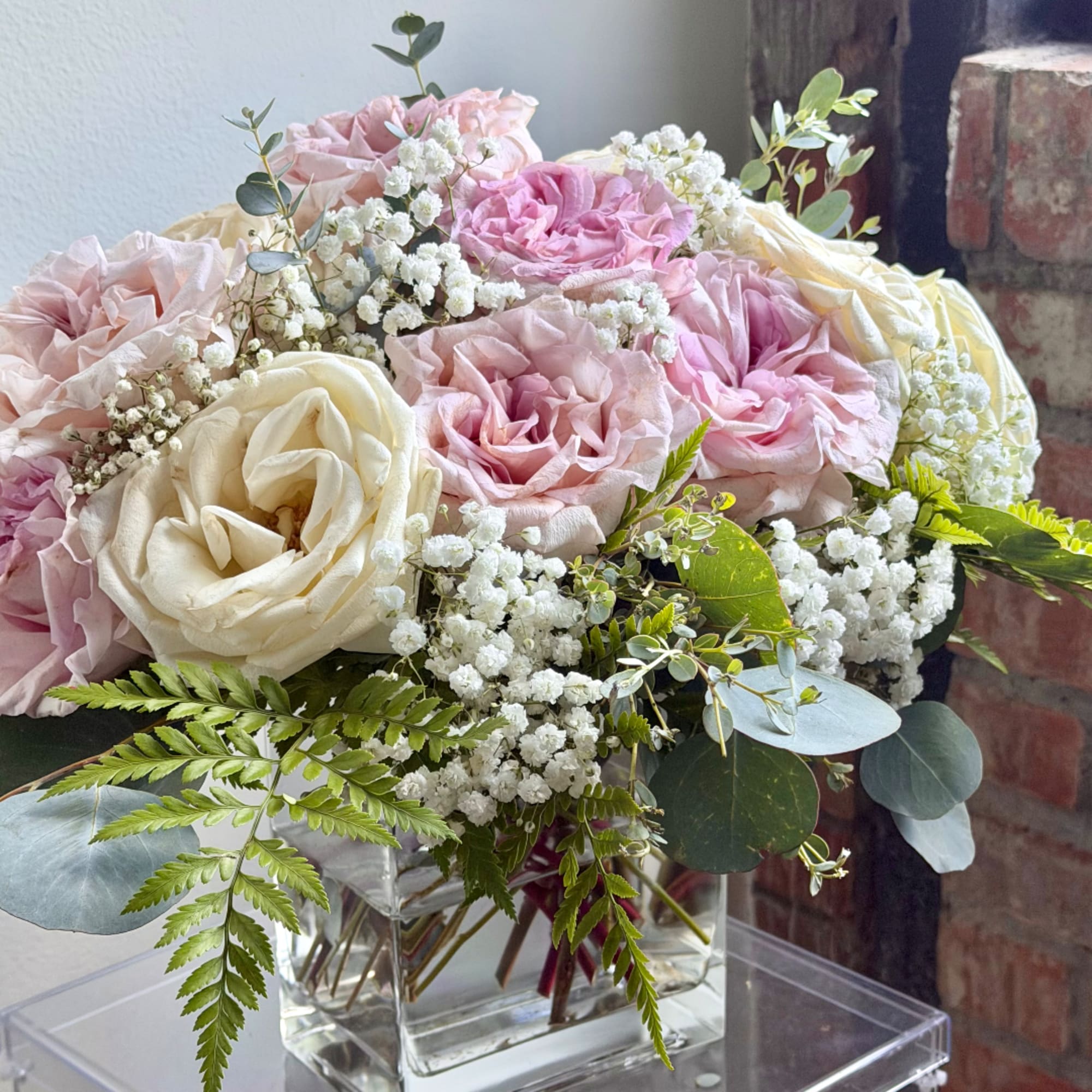 Pink and cream roses in a clear glass vase with baby's breath