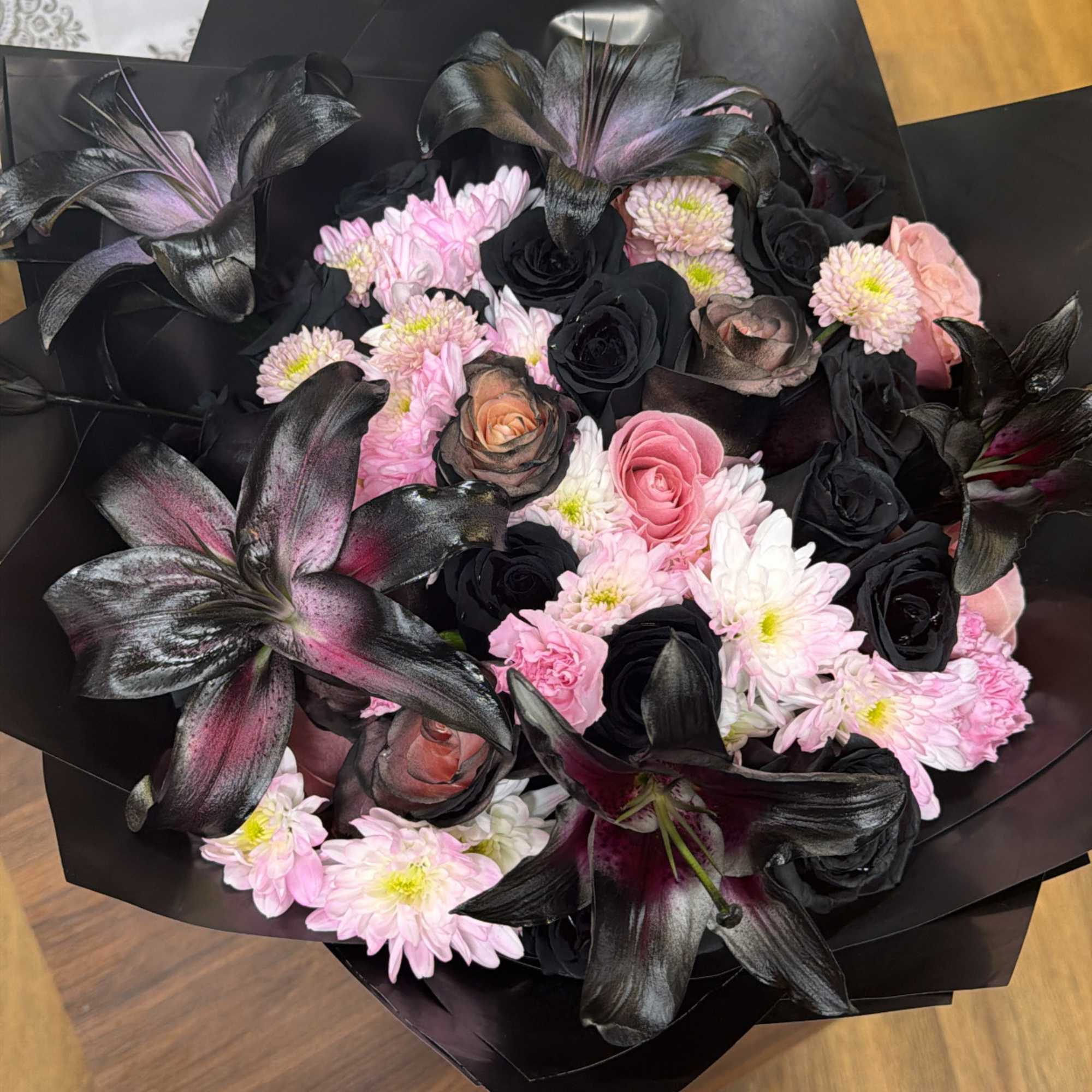 Bouquet of pink and black flowers wrapped in black paper