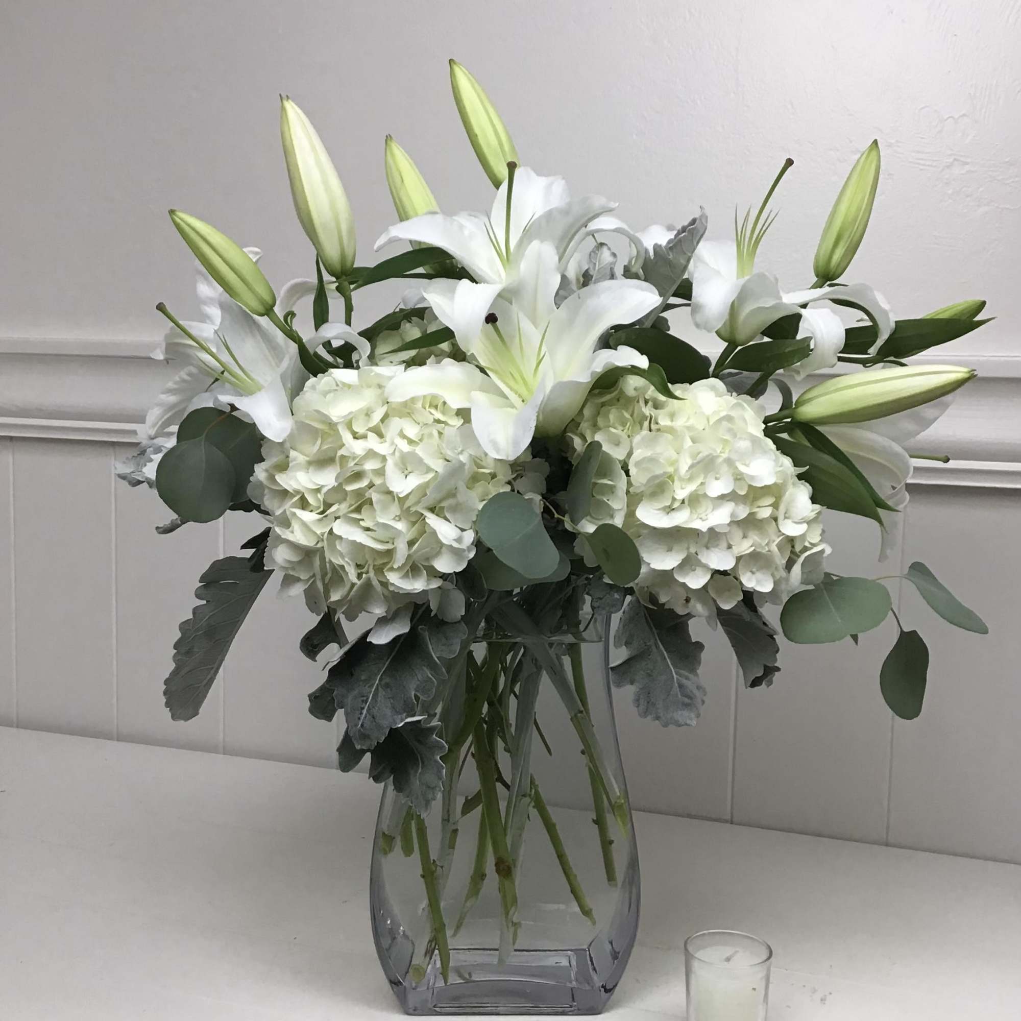 White lilies and hydrangeas in a clear glass vase