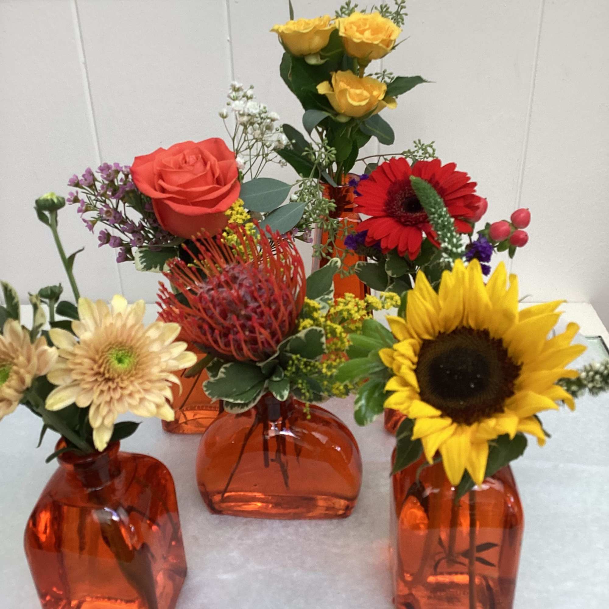 Small mixed flower arrangements in orange glass vases