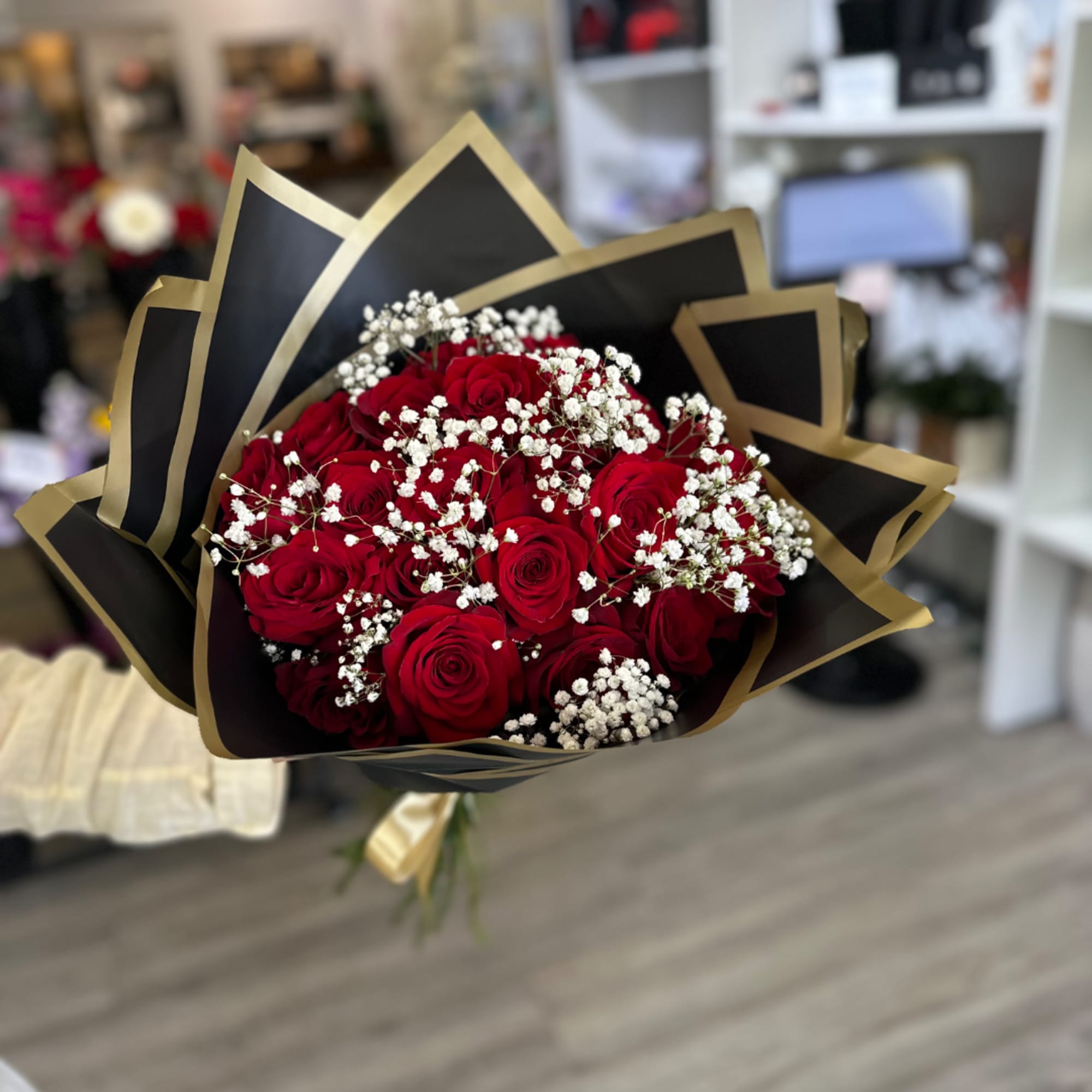 Bouquet of red roses with white baby's breath in black and gold wrap