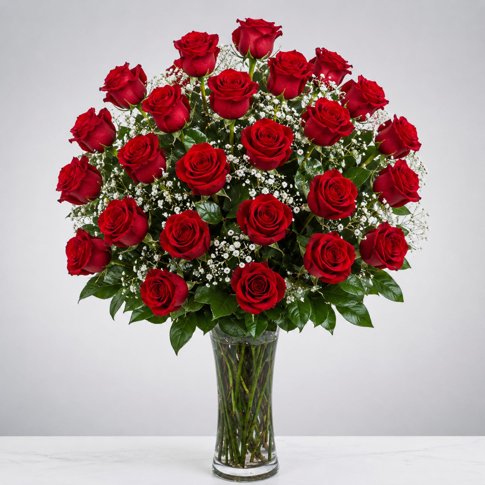 Bouquet of red roses with baby's breath in a clear glass vase