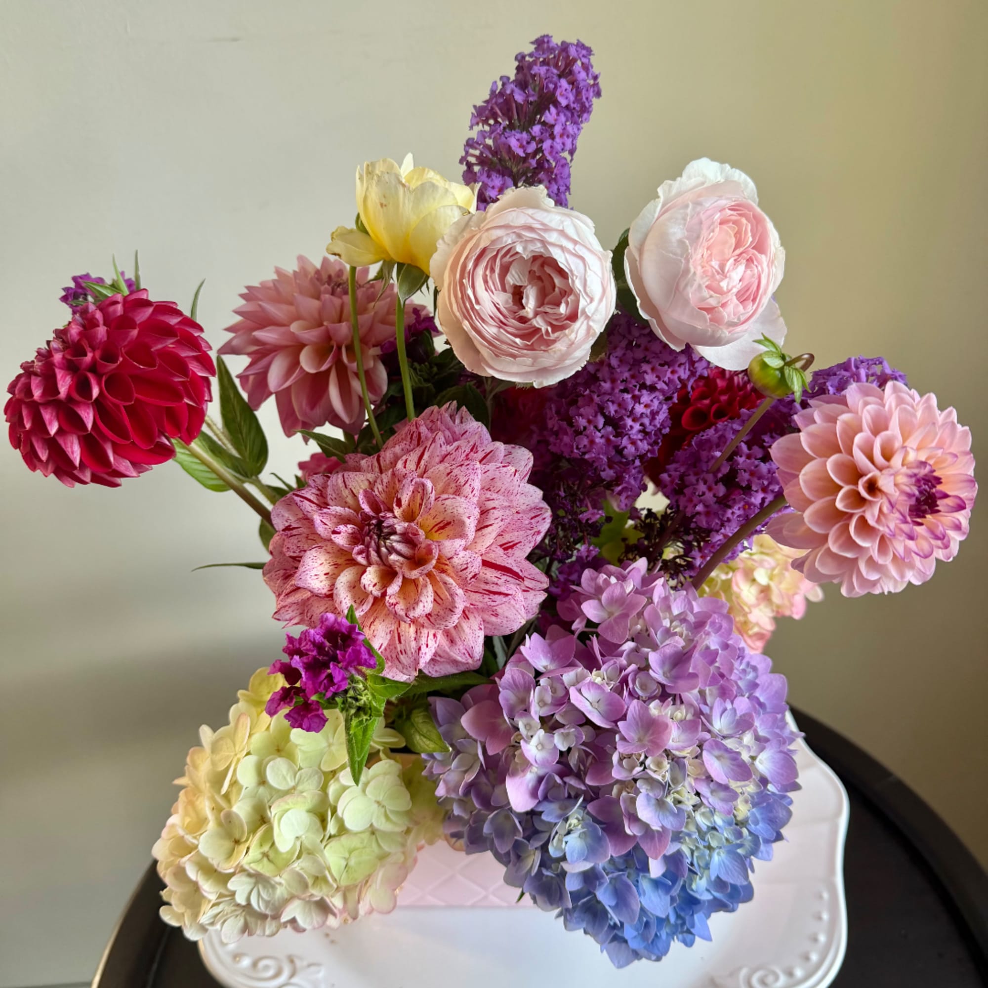 Mixed bouquet of pink, purple, yellow, and blue flowers in a white vase