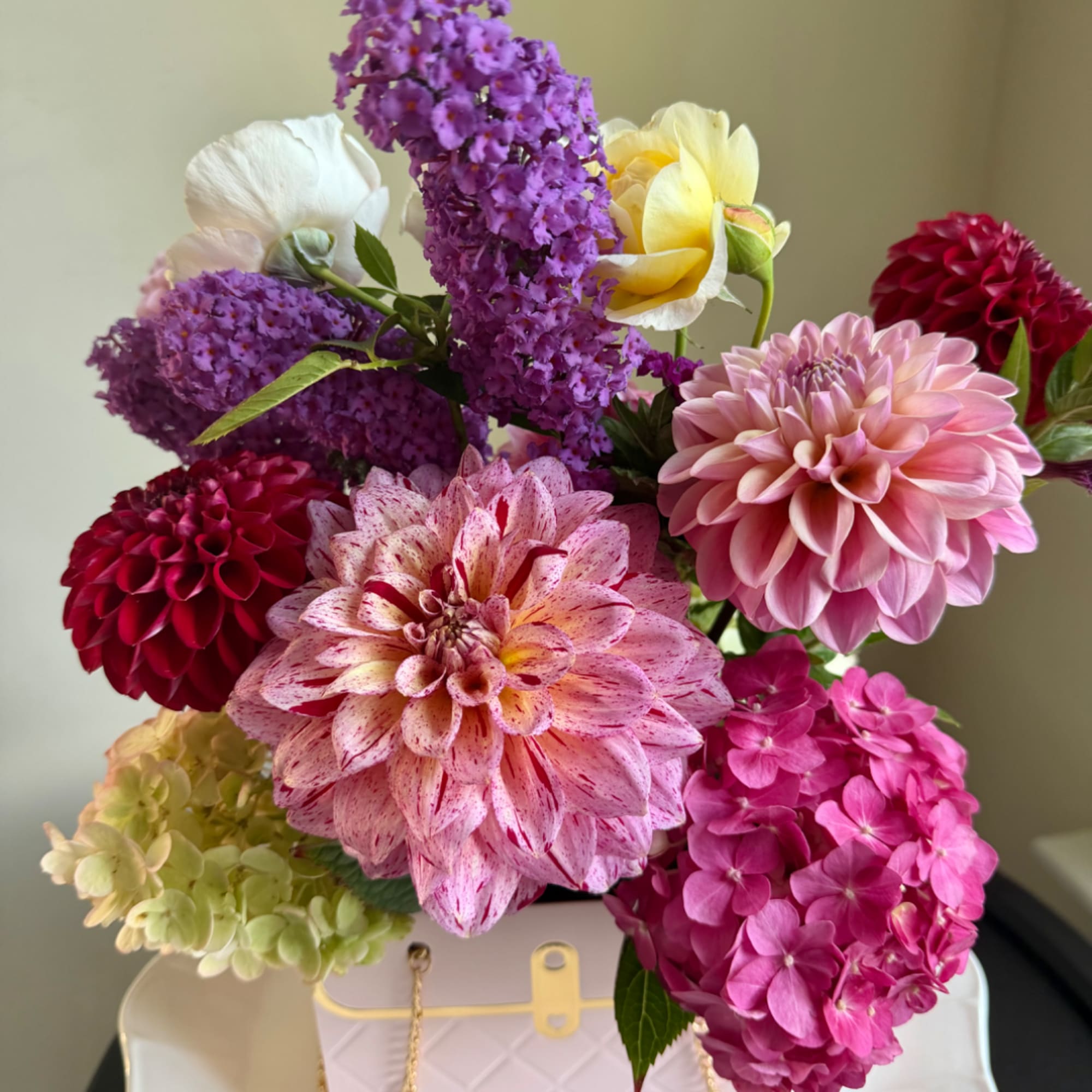 Mixed bouquet with dahlias, hydrangeas, and purple blooms in a white container