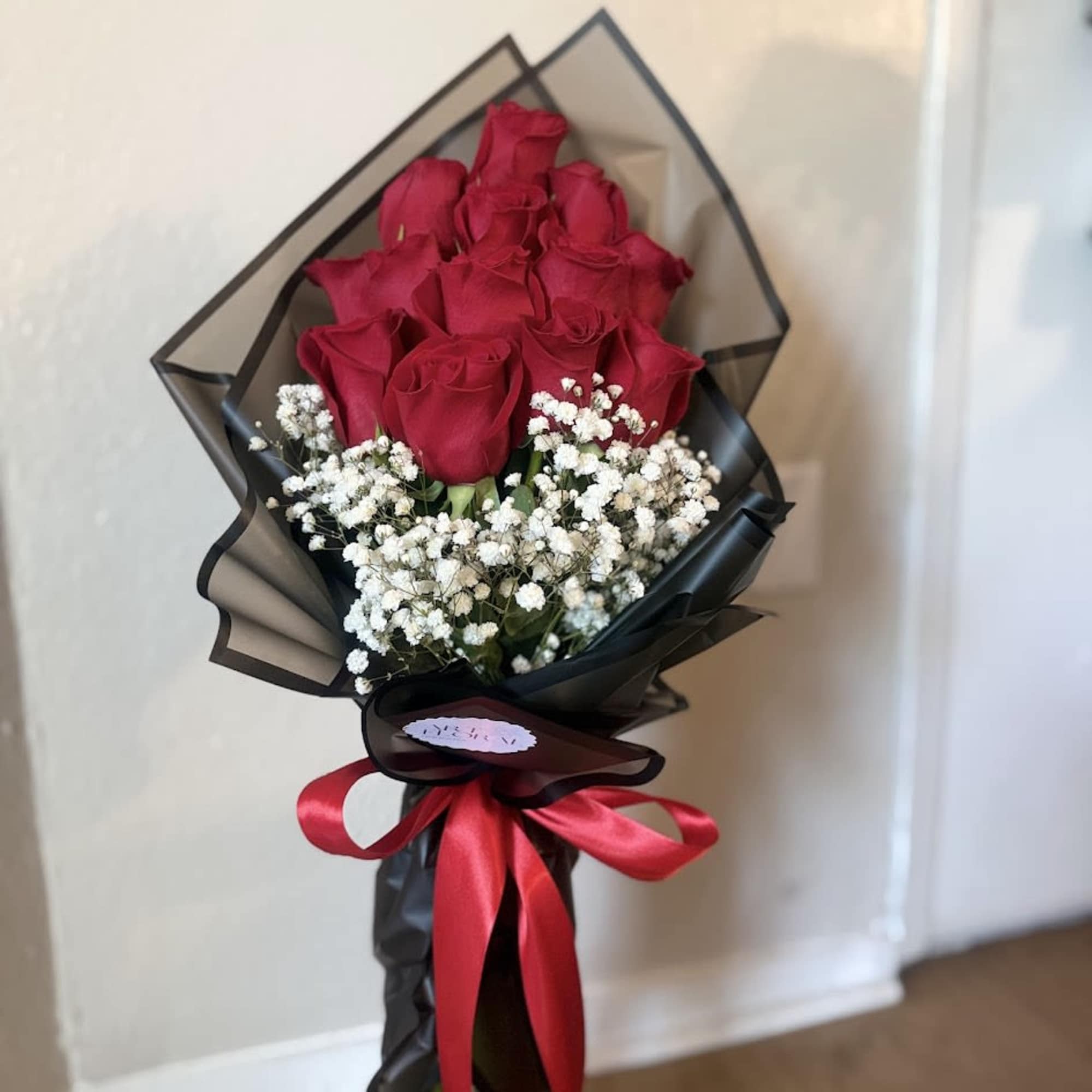 An elegant arrangement of fresh red roses, accompanied by delicate gypsophila that