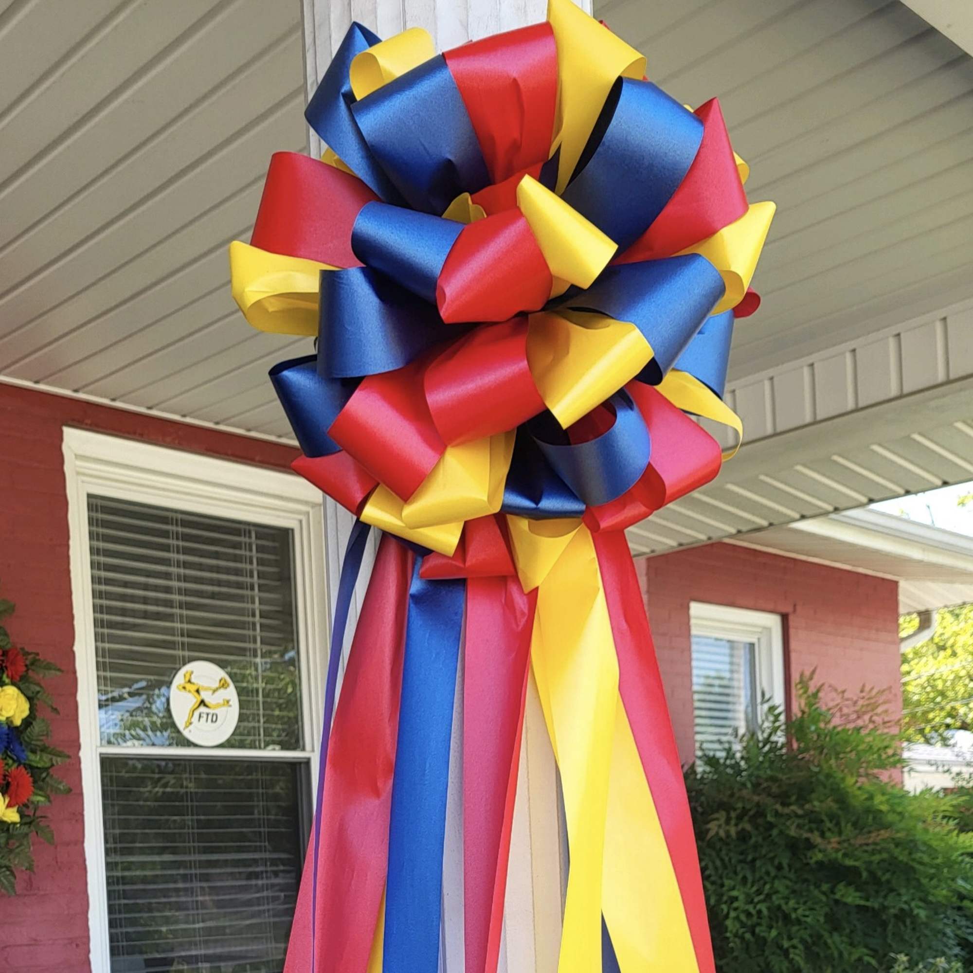 Large red, blue, and yellow ribbon bow hanging outdoors