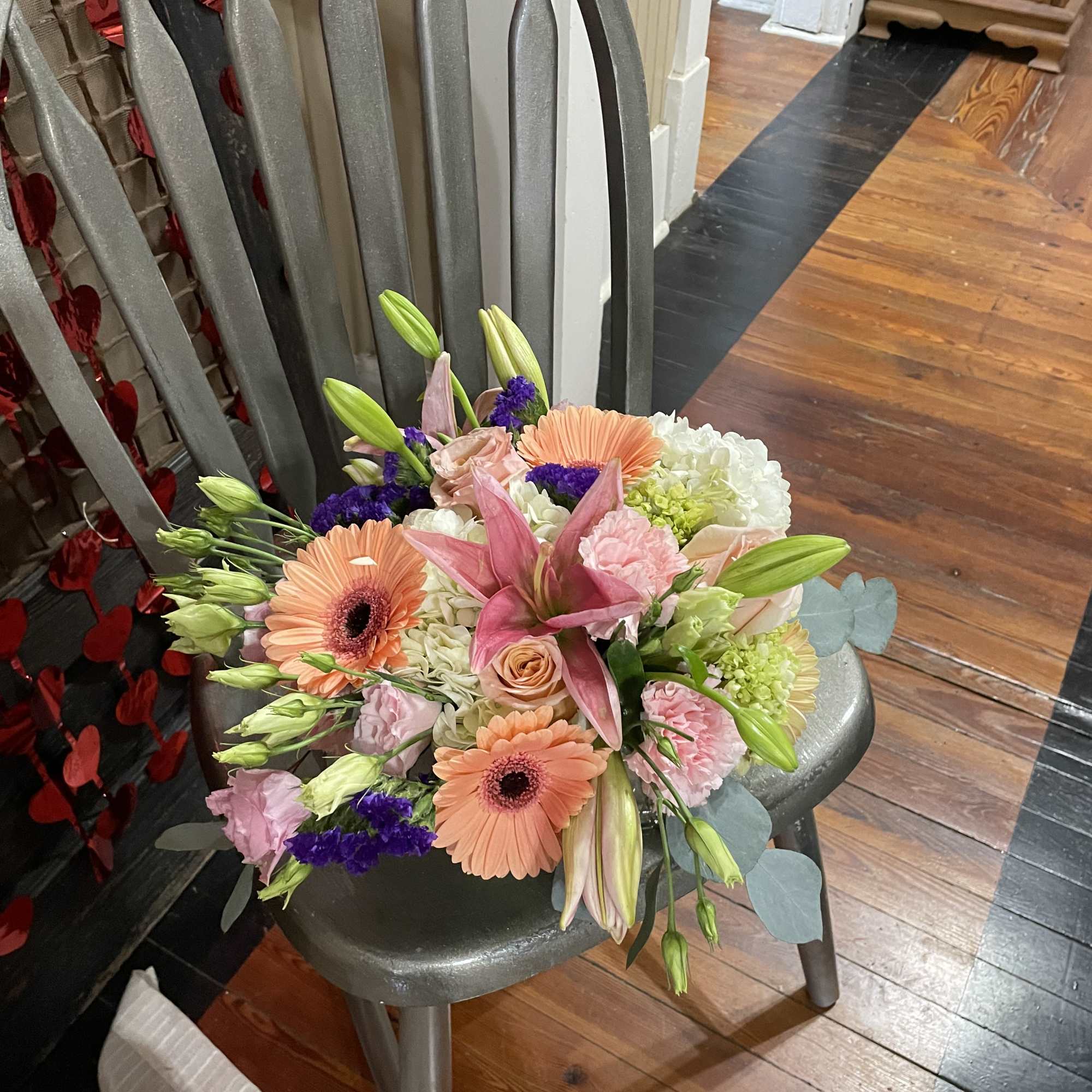 Mixed bouquet with pink lilies, peach gerbera daisies, and pastel roses on a chair