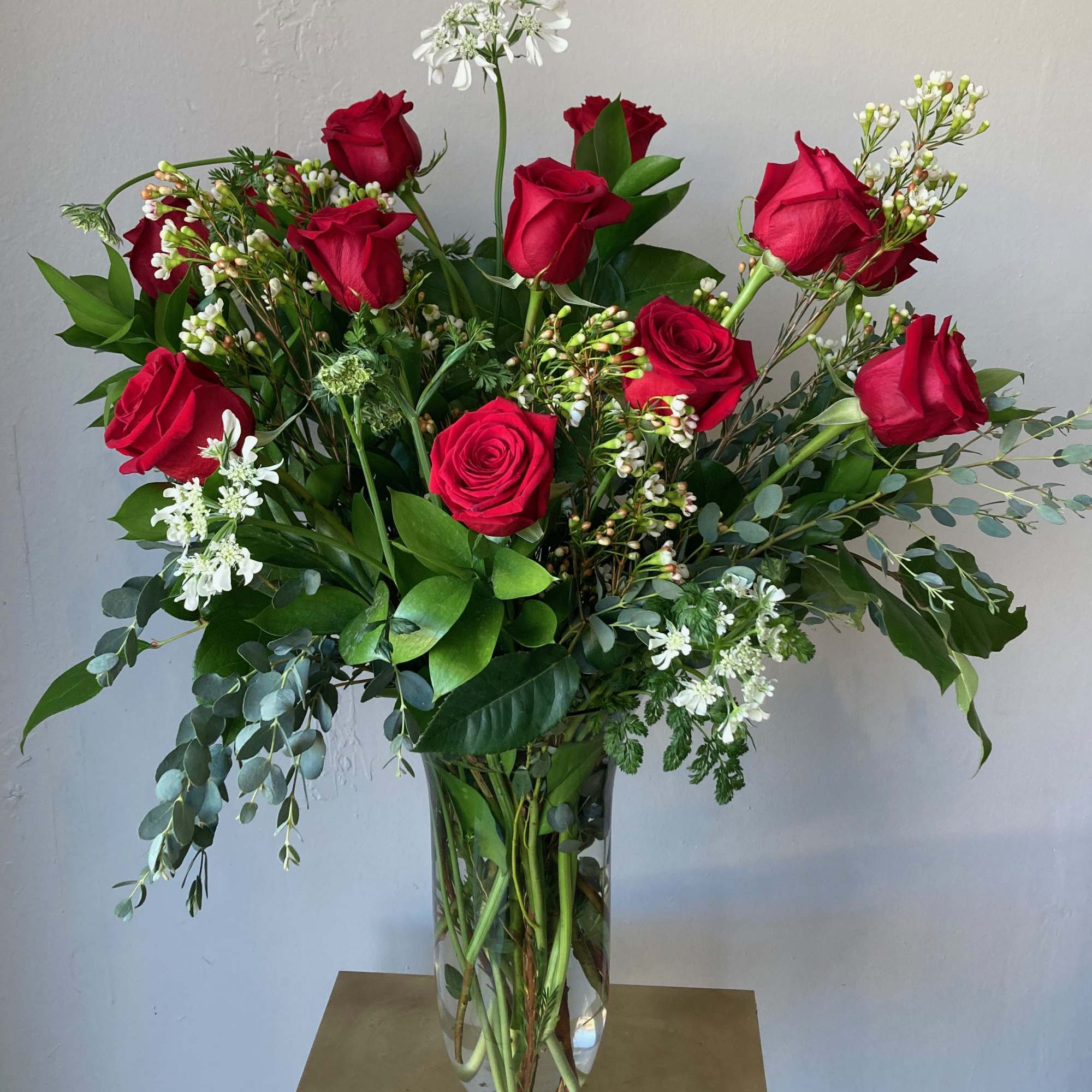 Red roses in a clear glass vase with white filler flowers