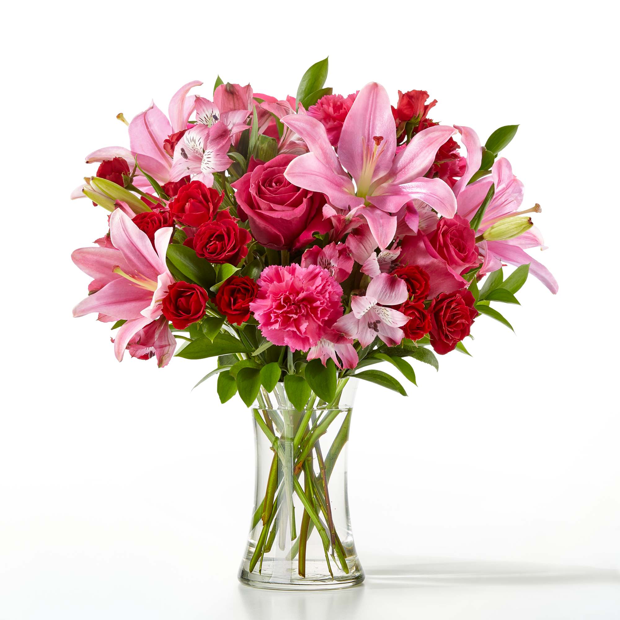 Pink lilies and red roses arranged in a clear glass vase