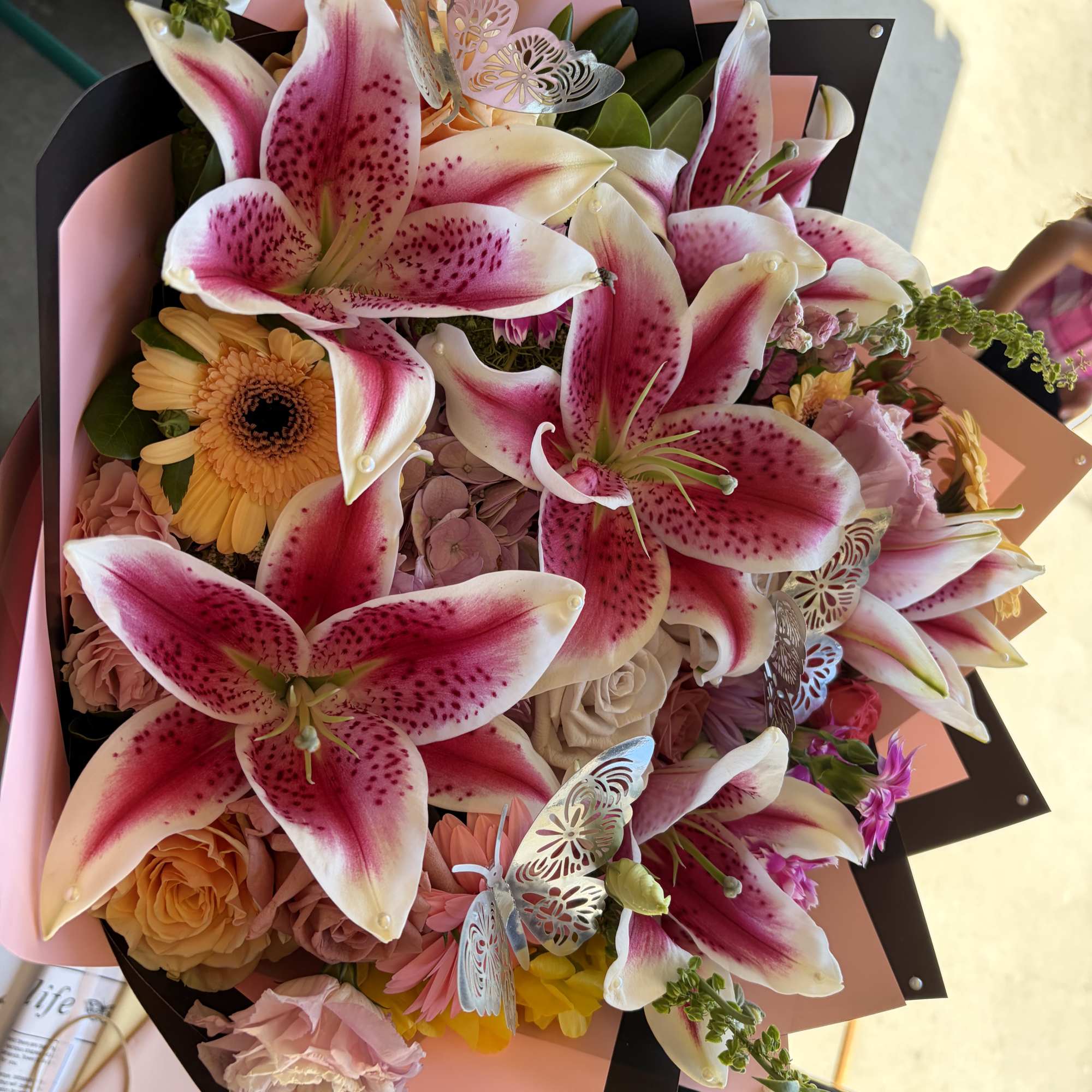 Bouquet of pink stargazer lilies and peach roses with butterfly accents