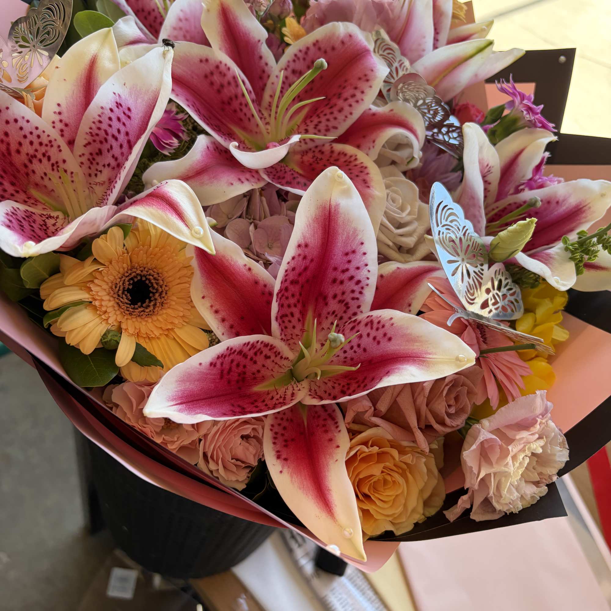 Bouquet of pink stargazer lilies, roses, and gerbera daisies in black and pink wrap