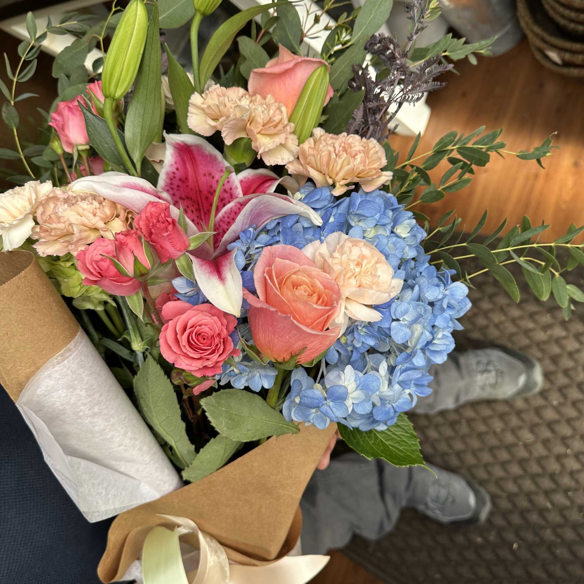 Hand-tied bouquet with pink roses, blue hydrangeas, lilies, and carnations