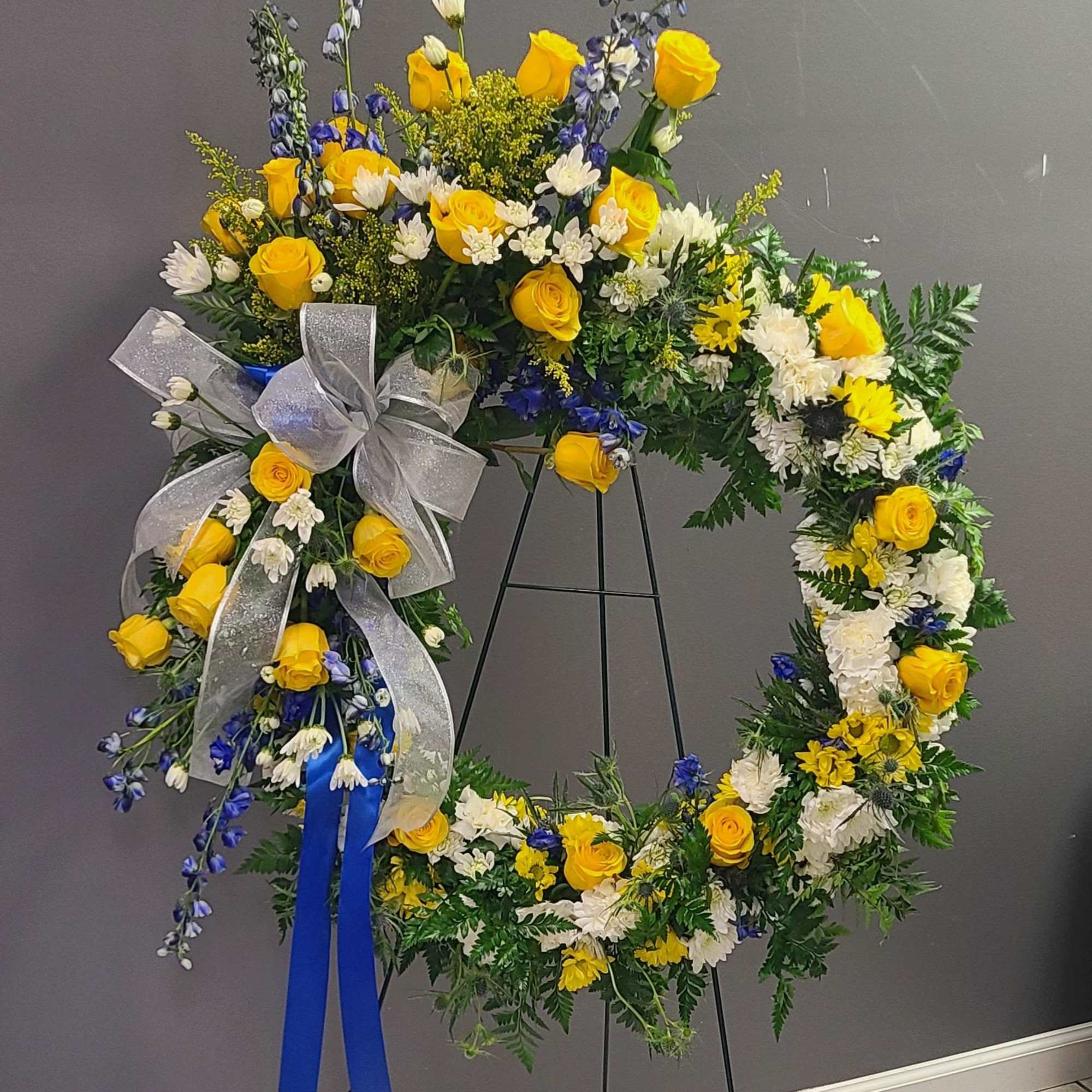 A bright halo of yellow roses and white daisy-like blooms makes this