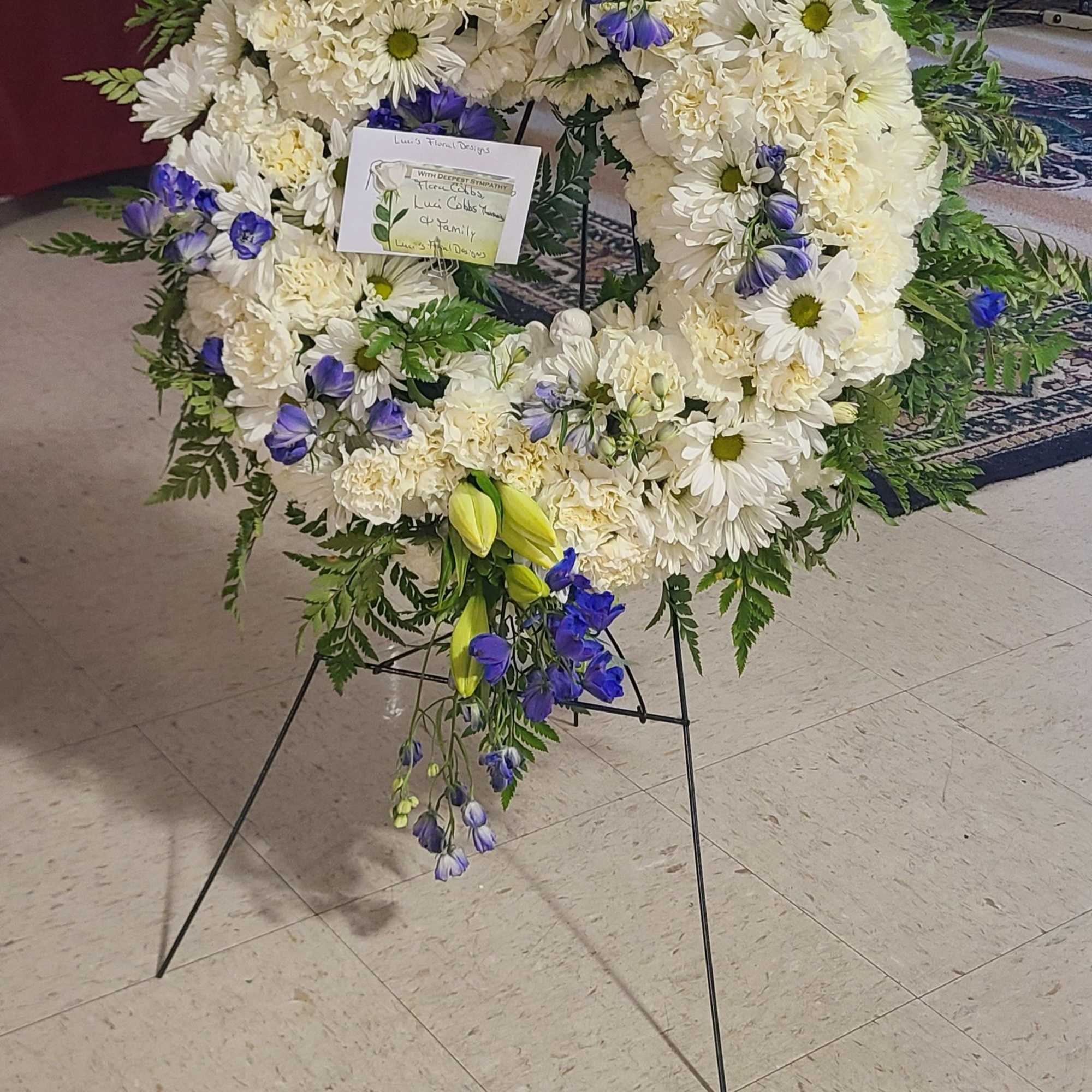 A serene white sympathy wreath with vivid blue accents offers a respectful