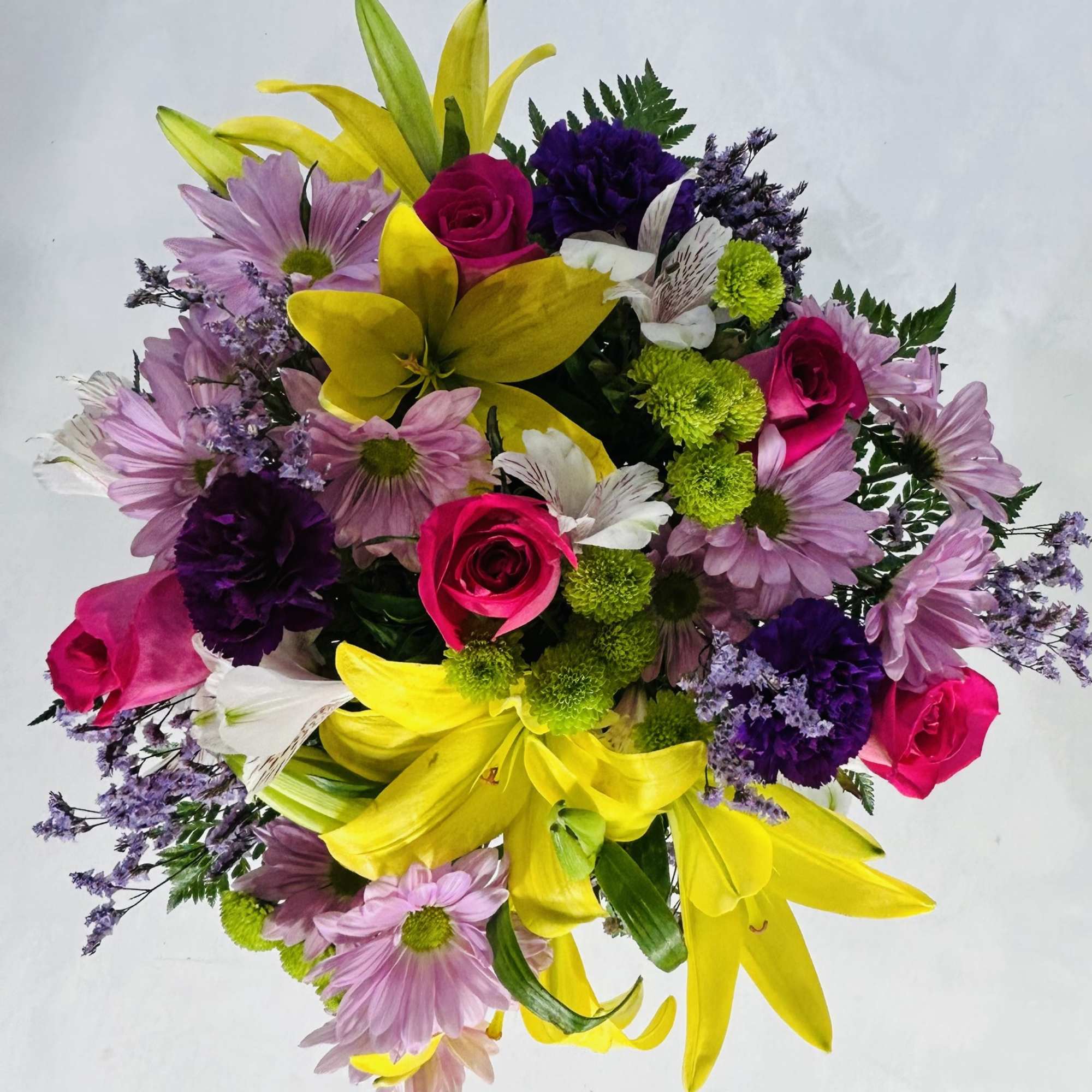 Bright mixed bouquet with yellow lilies, pink roses, purple carnations and lavender daisy mums