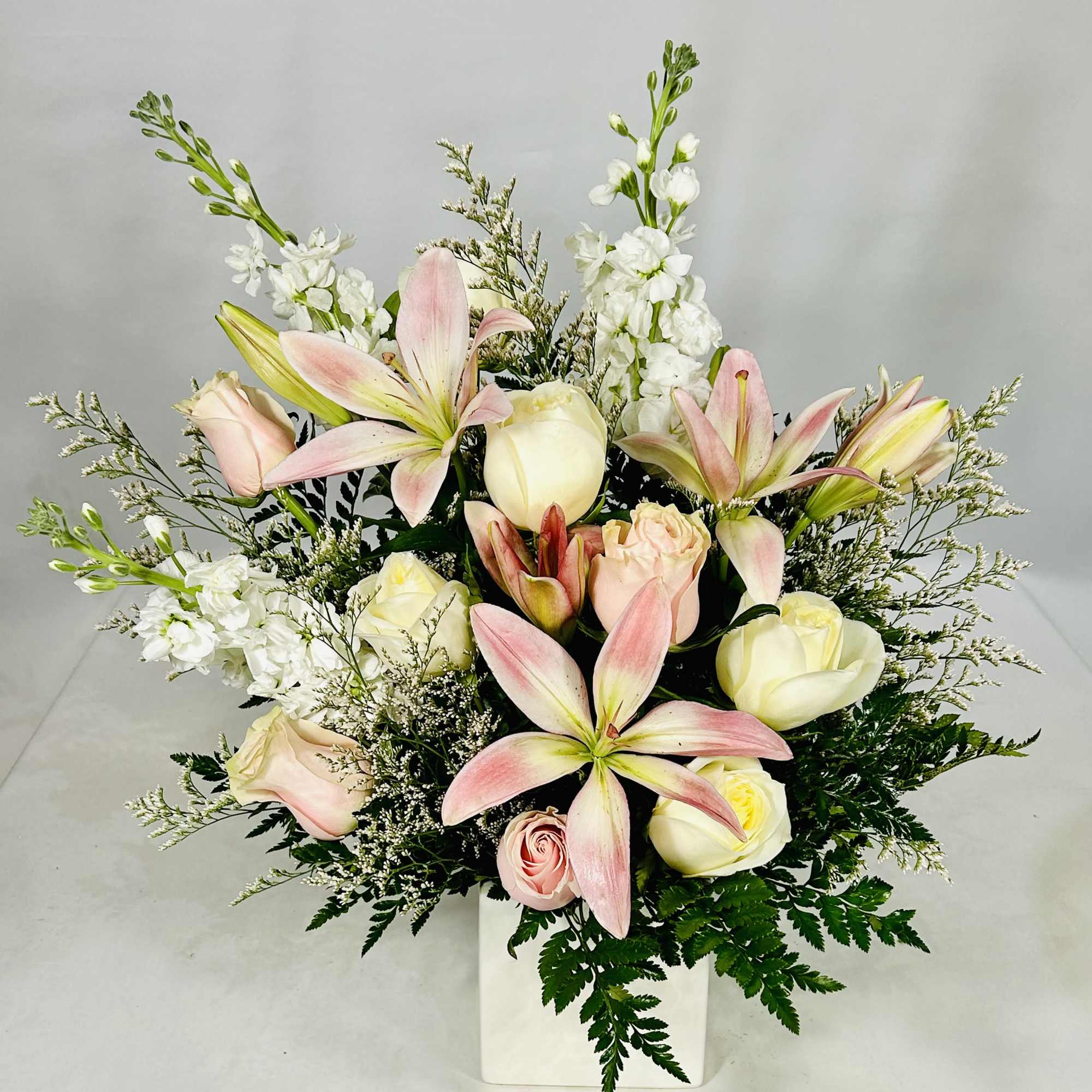 Pink lilies and cream roses in a white vase
