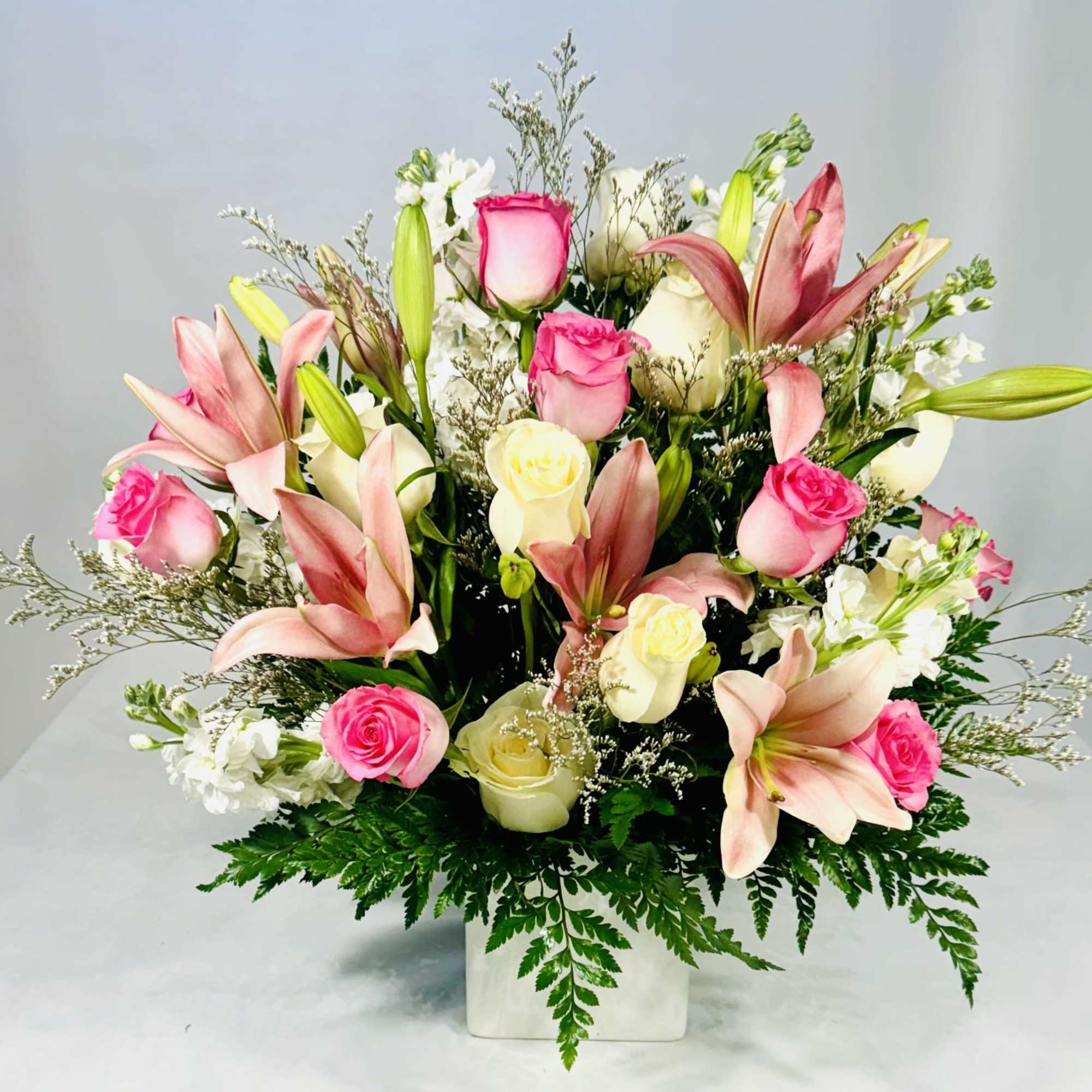 Pink and white roses with lilies in a white vase