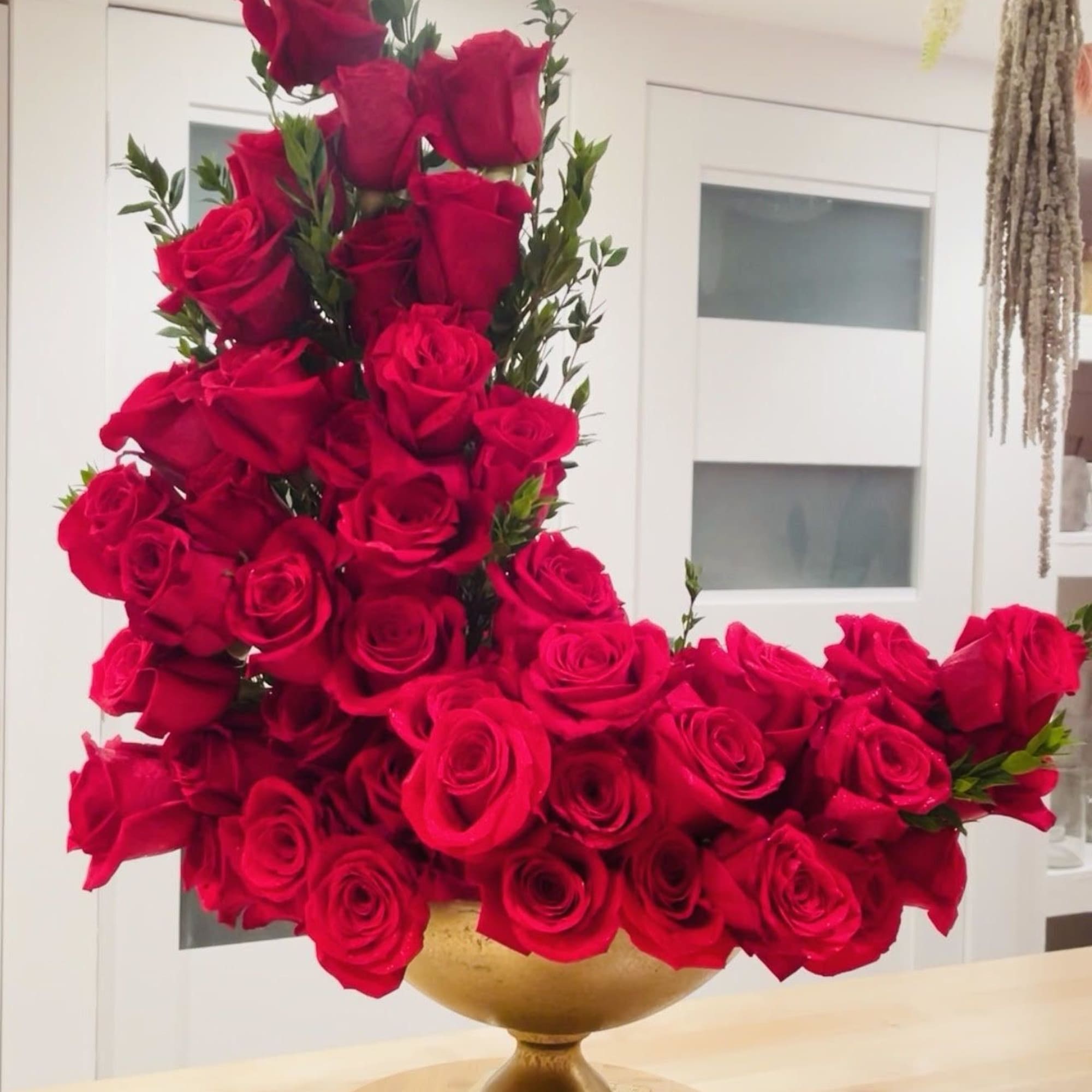 Large arrangement of red roses in a gold vase