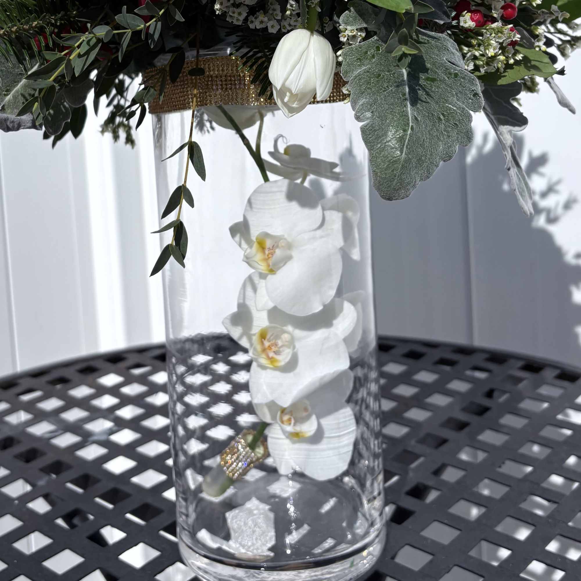 White orchid stems in a clear glass vase with greenery