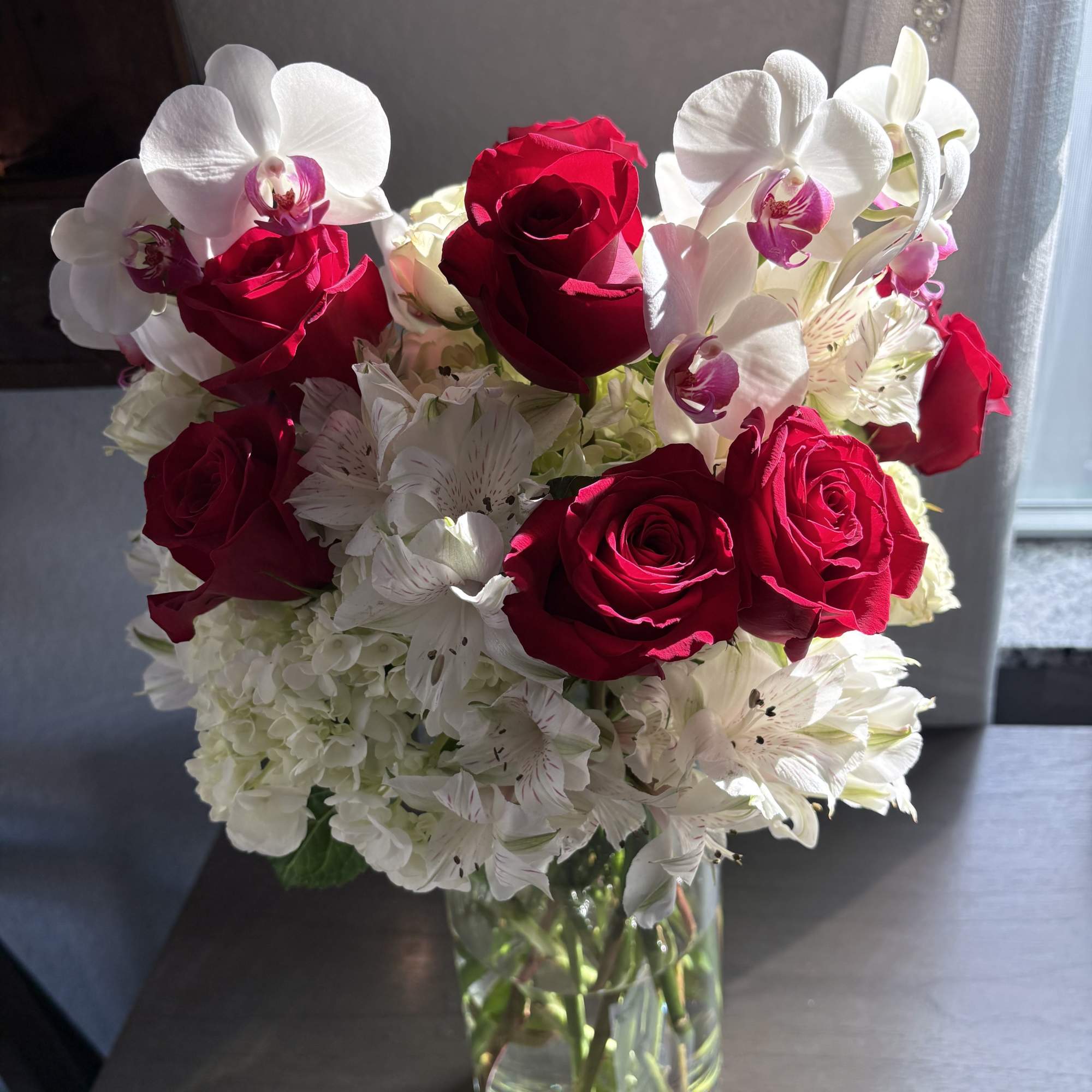 Red roses and white orchids in a clear glass vase
