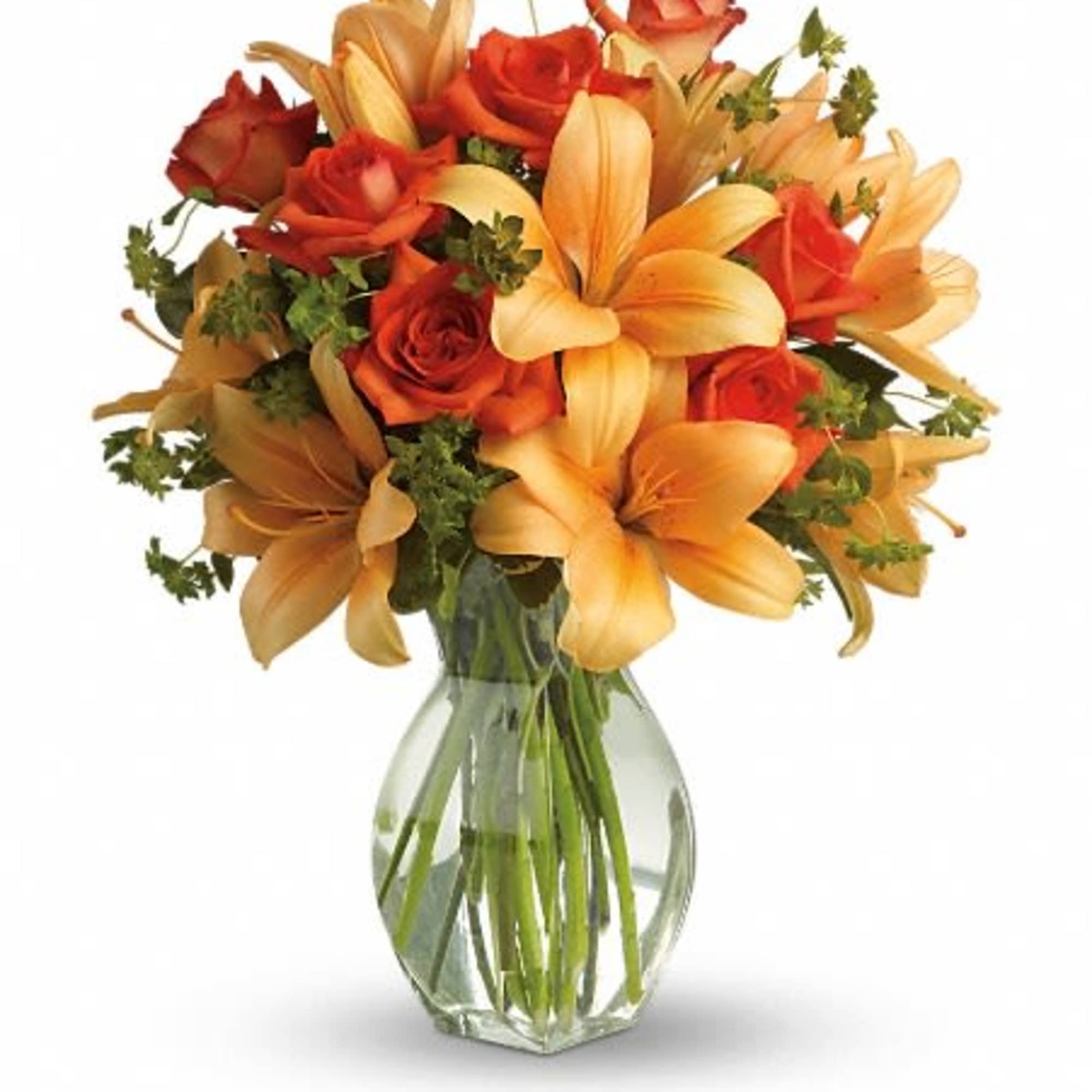 Orange lilies and red roses arranged in a clear glass vase