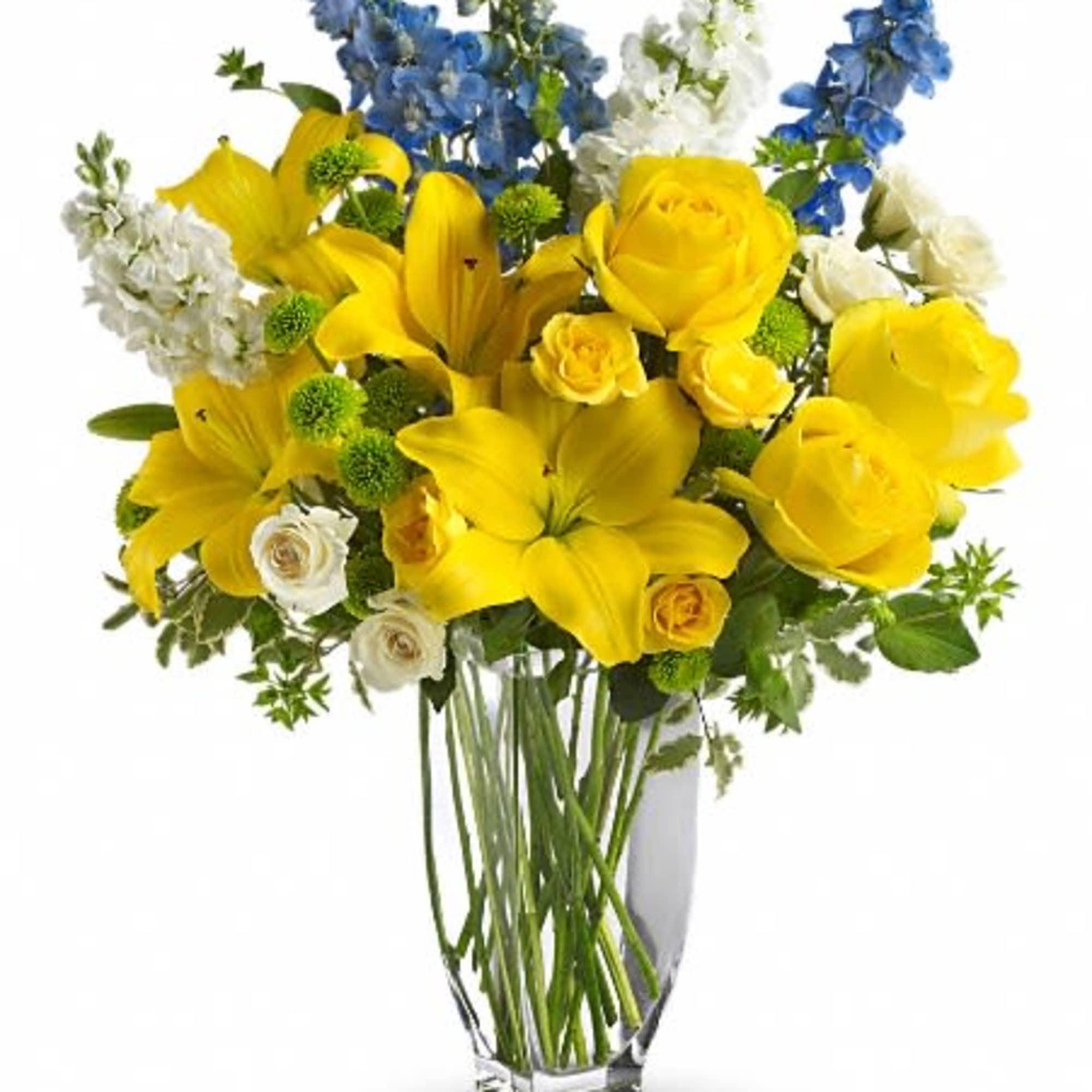 Yellow roses and lilies in a clear glass vase with blue and white flowers