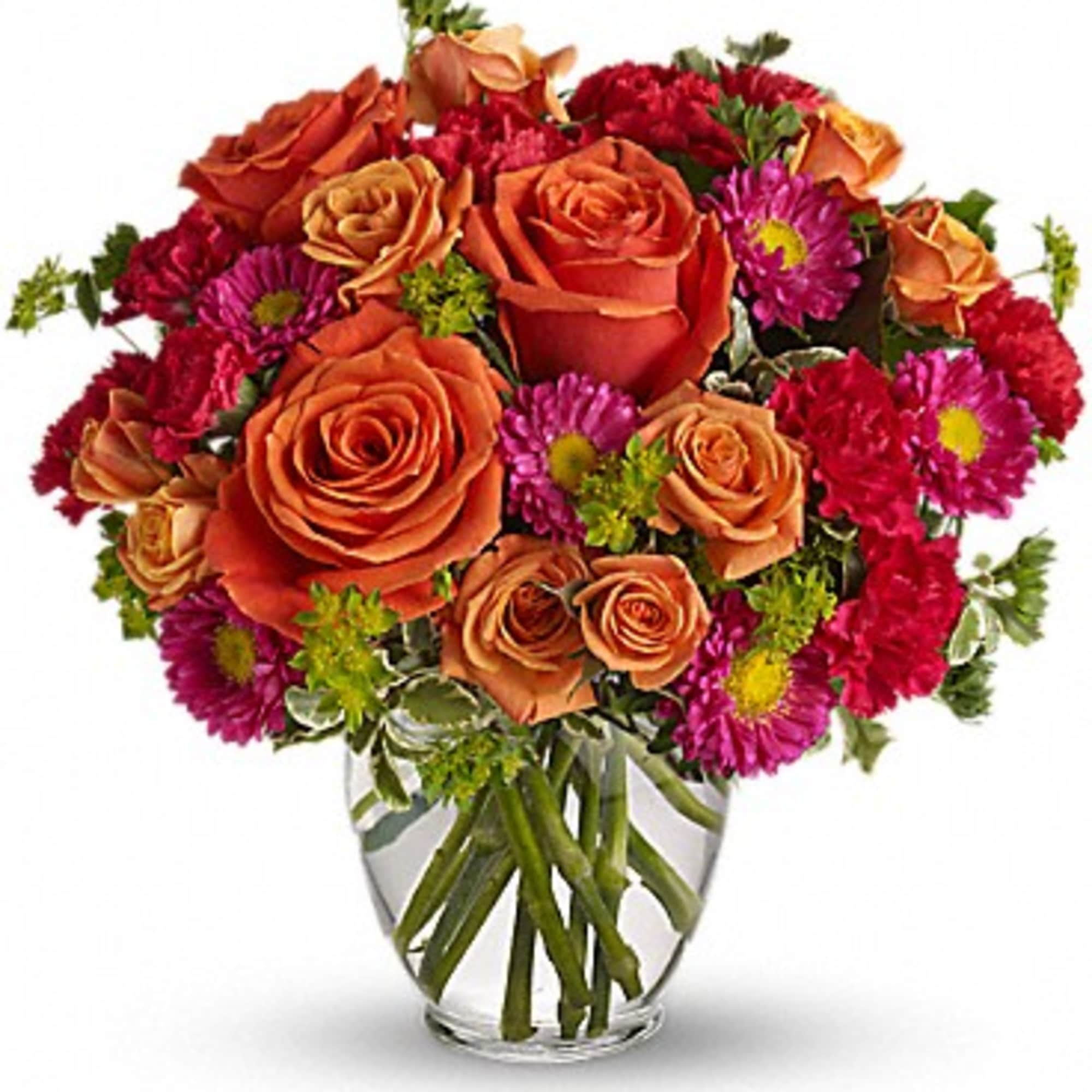 Orange roses and magenta daisies in a clear glass vase