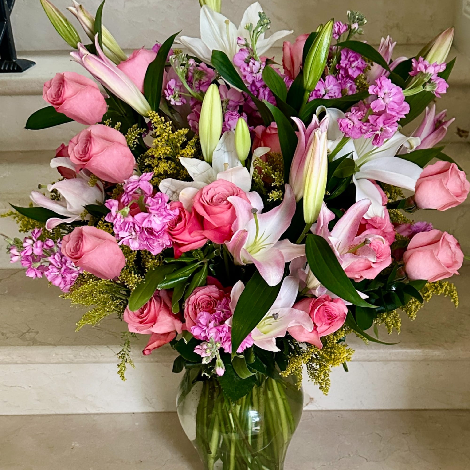 Pink roses and lilies arranged in a clear glass vase
