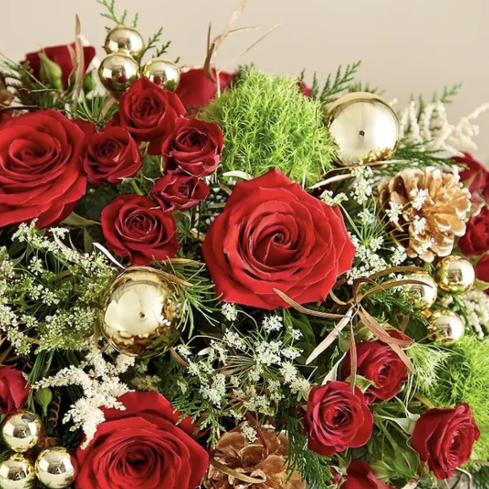 Red roses with gold ornaments and pinecones in a festive arrangement