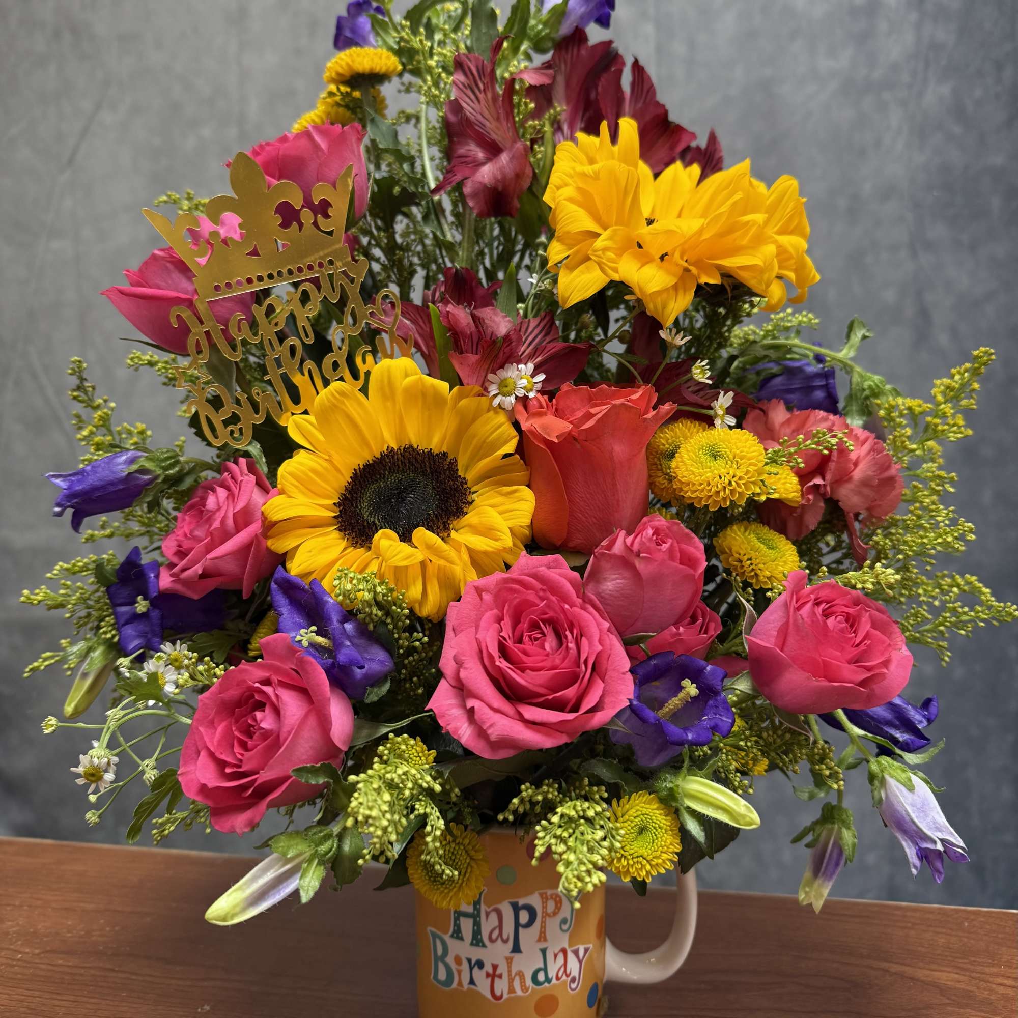 Birthday bouquet in a mug with roses, sunflowers, and mixed blooms