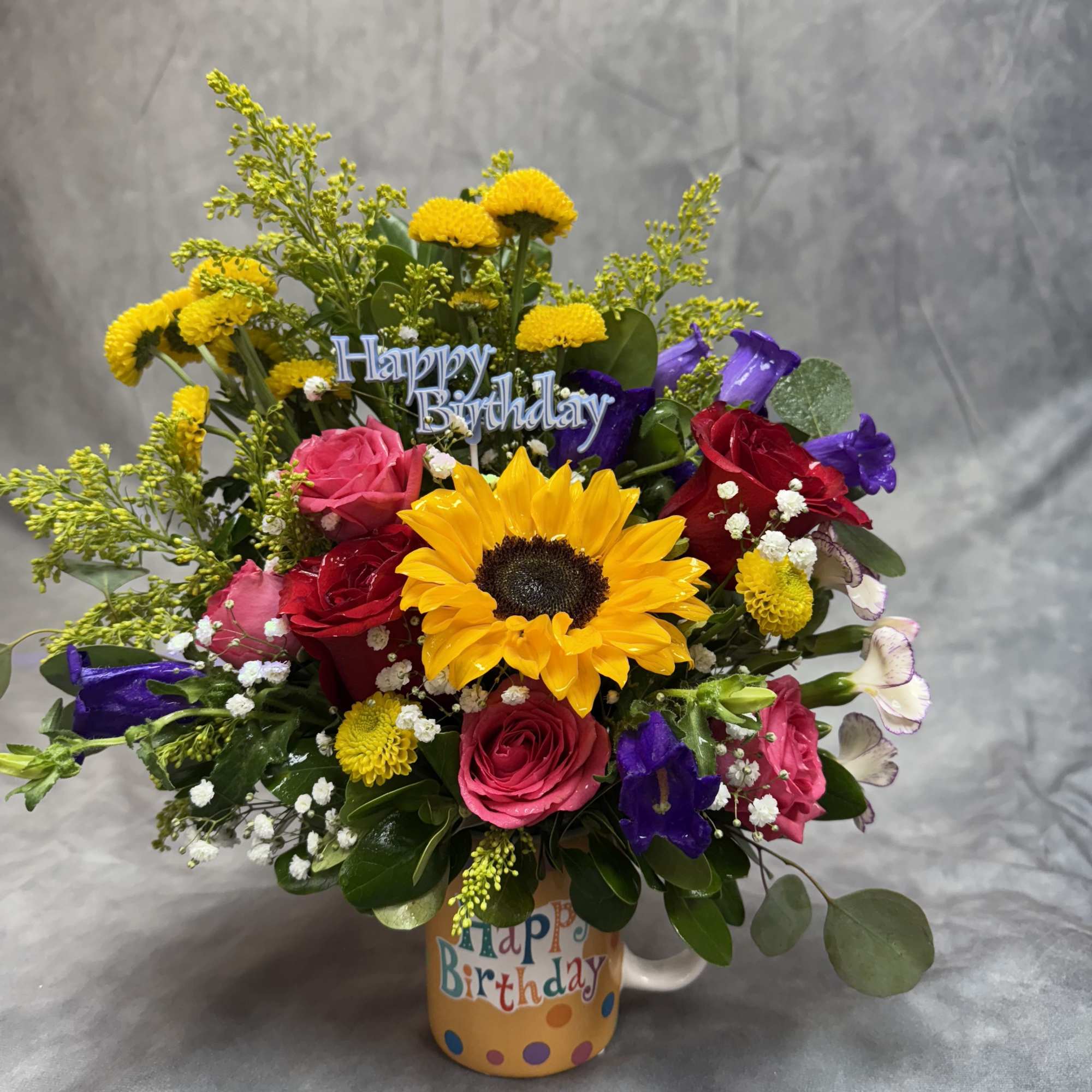 Colorful birthday bouquet in a mug with roses and a sunflower
