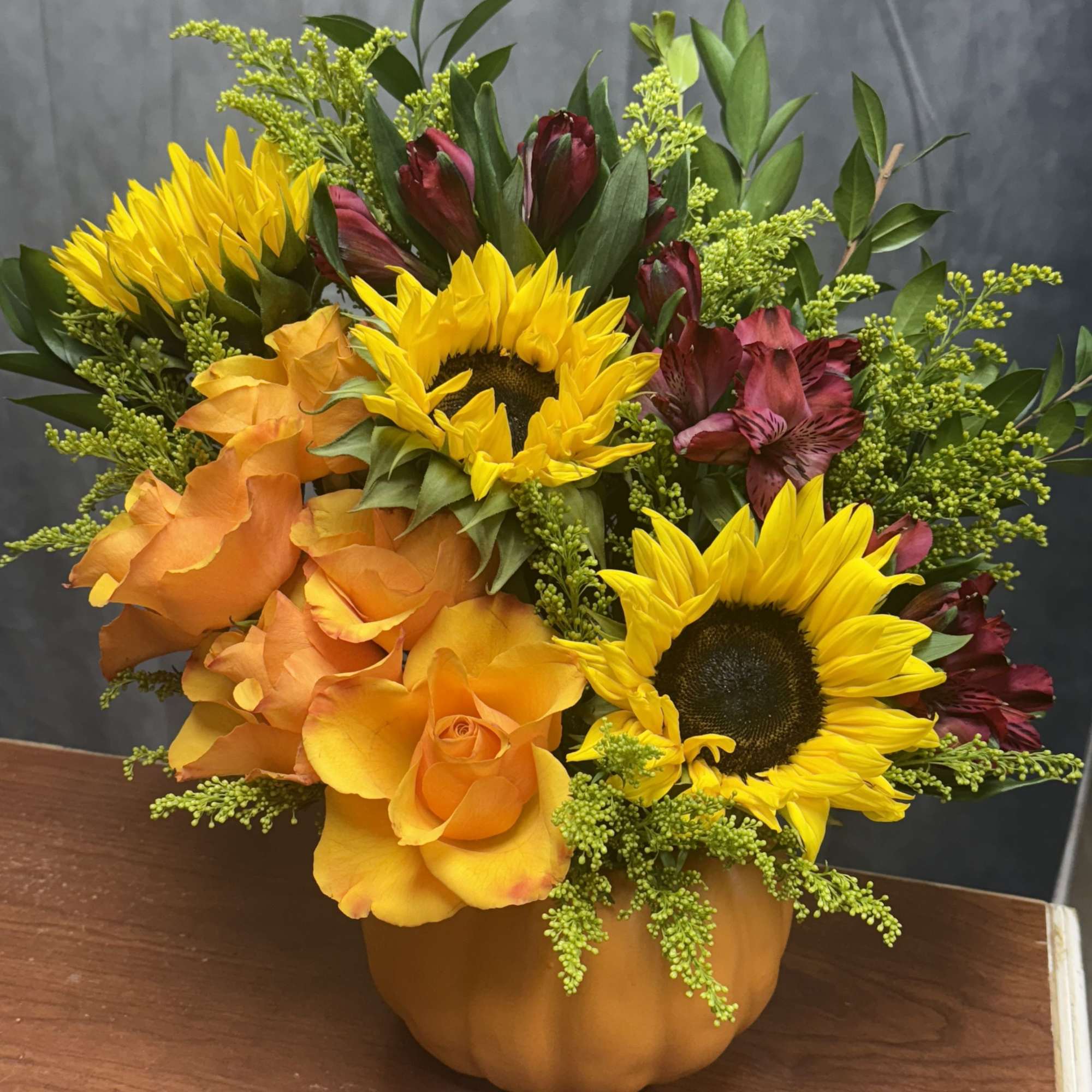 A warm, cheerful fall arrangement bursting with seasonal charm. 
This design features