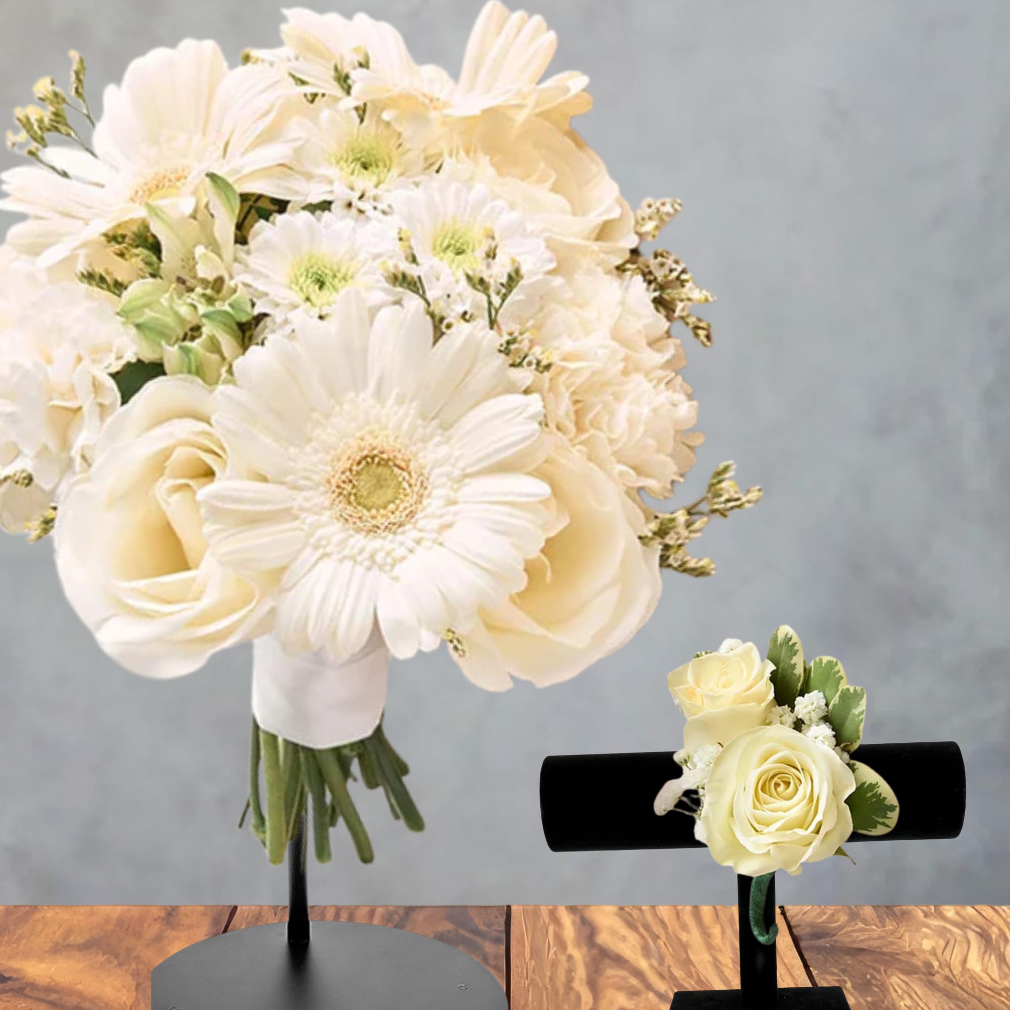 Cream bouquet with roses and daisies on a stand beside a rose boutonniere