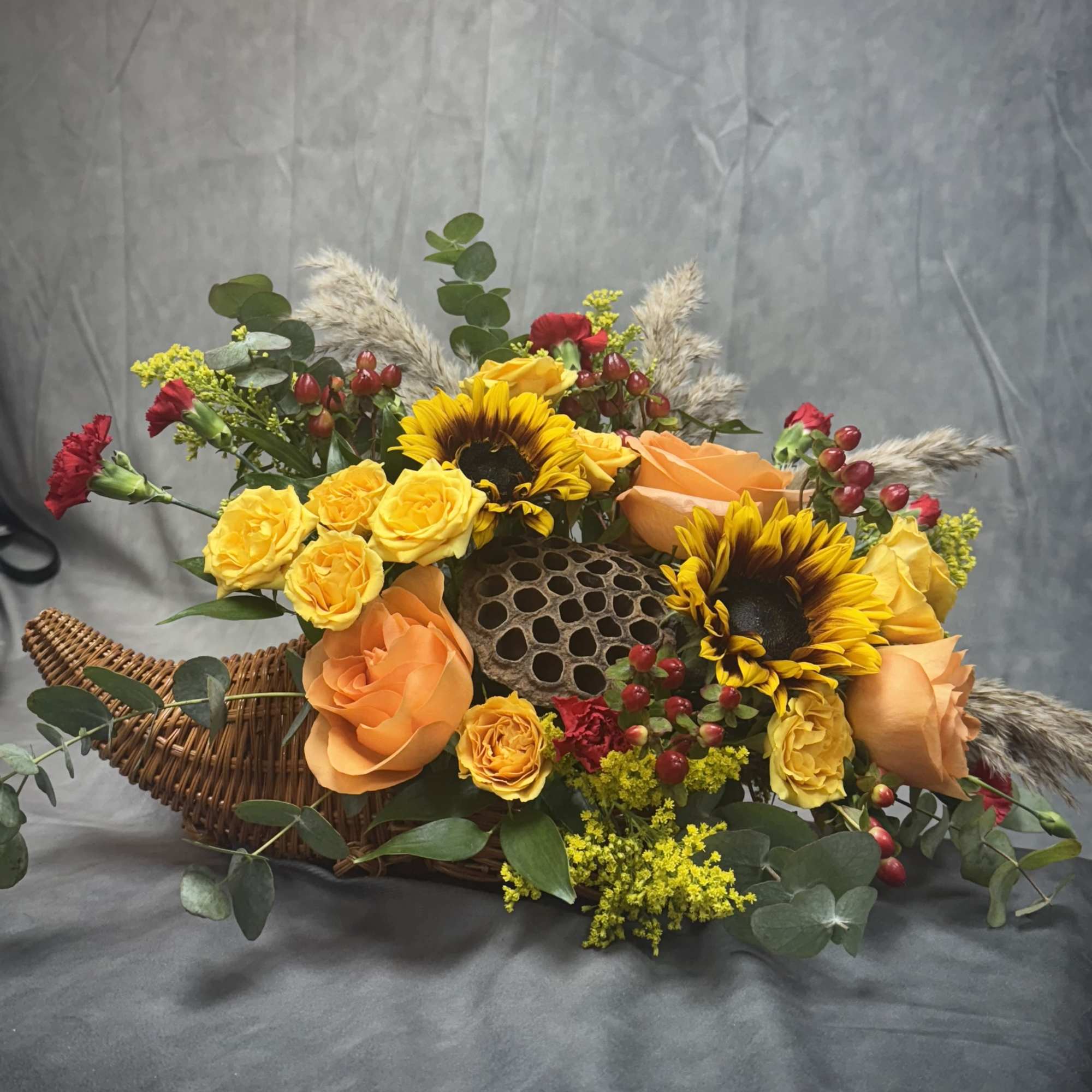 Introducing our Harvest Cornucopia a stunning arrangement featuring vibrant sunflowers and unique