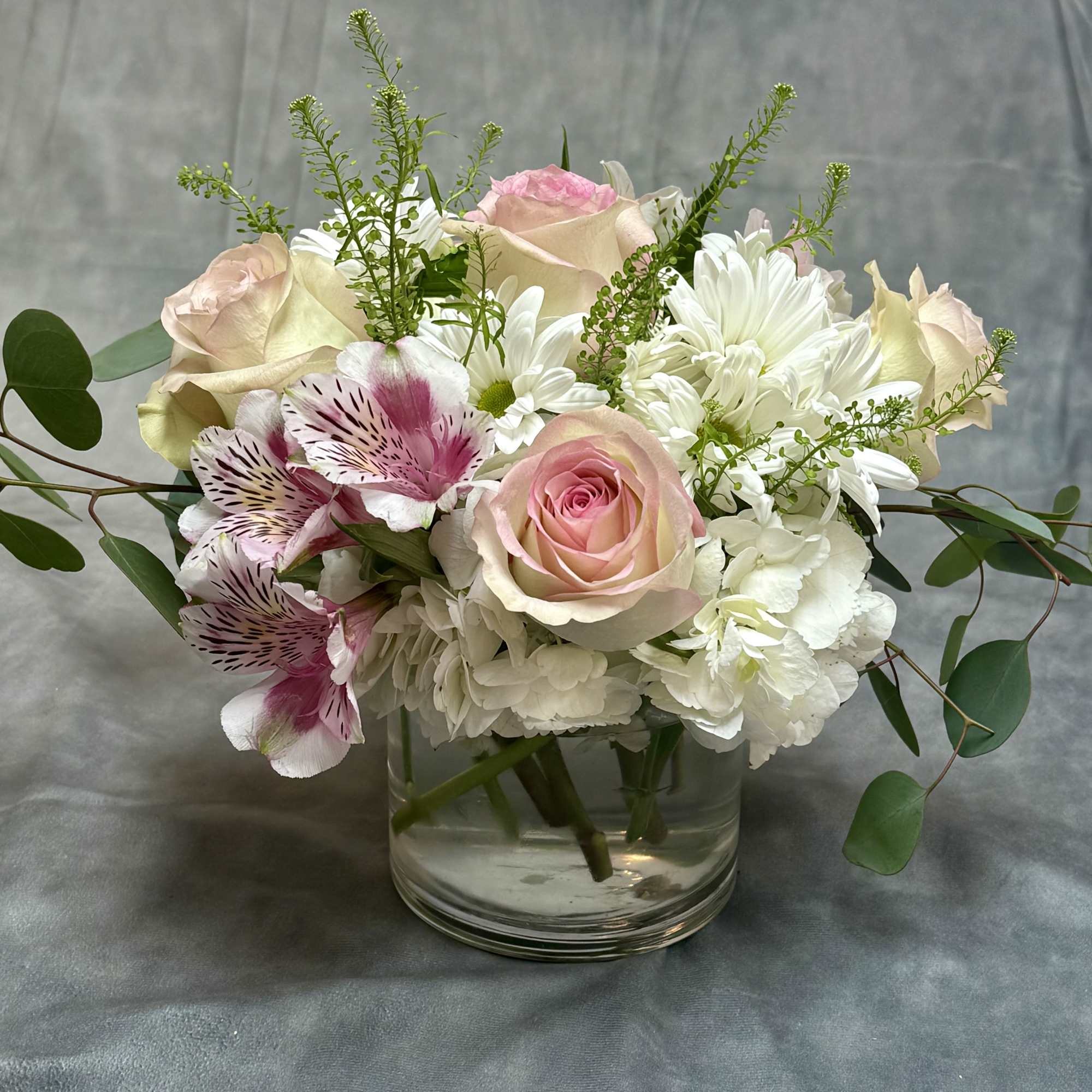 Pink and white roses with alstroemeria in a clear glass vase