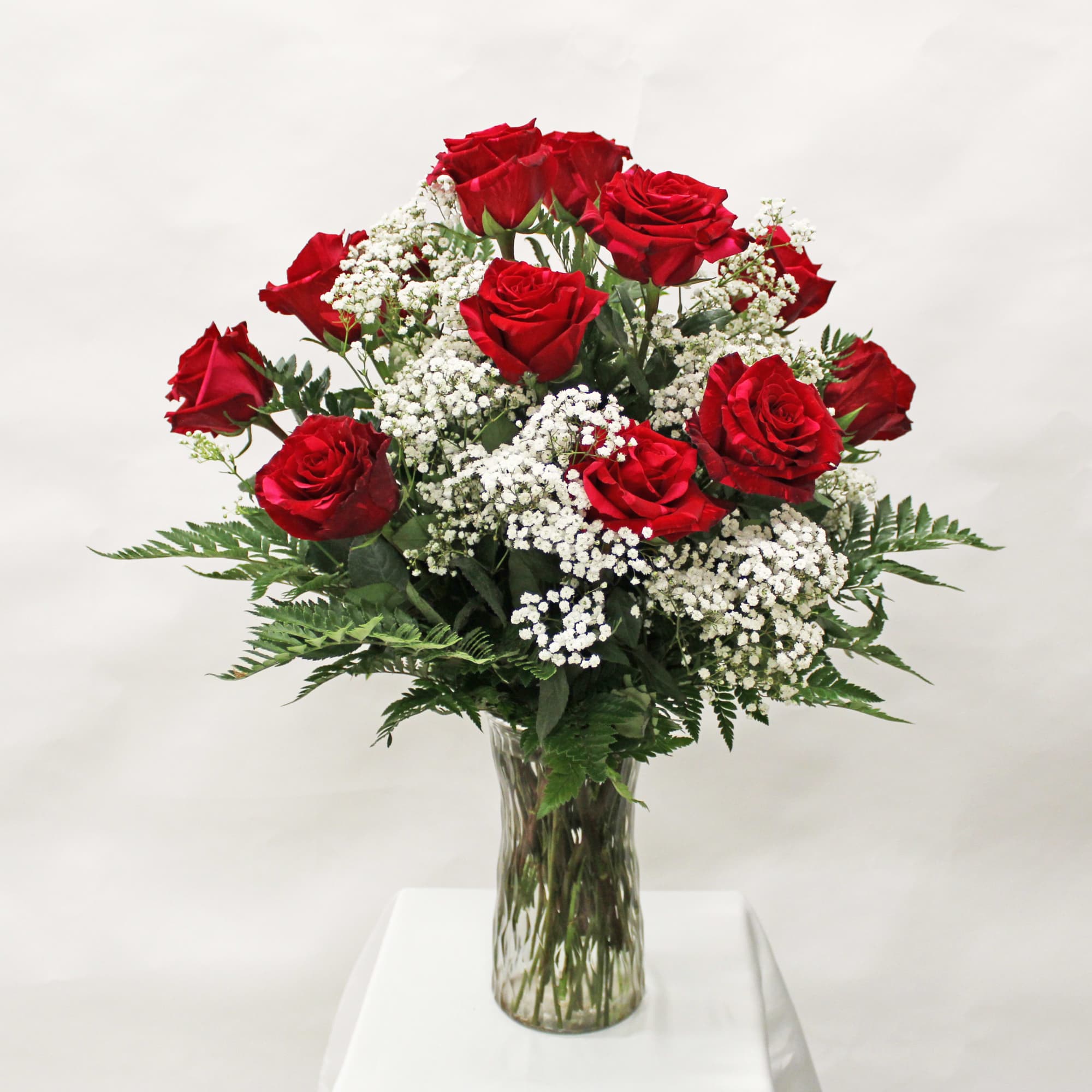 Arrangement of red roses and white filler flowers in a clear glass vase