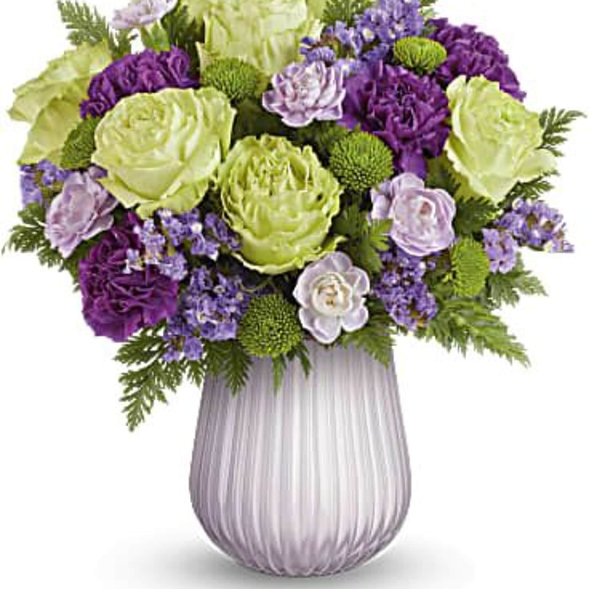 Purple and green floral arrangement in a ribbed lavender vase