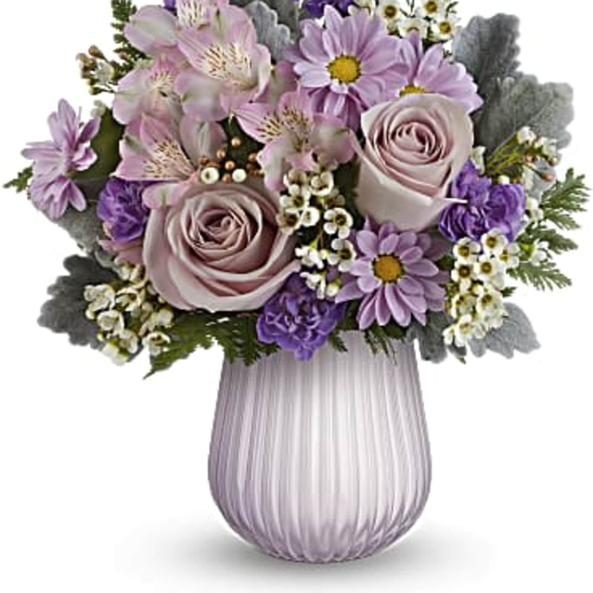 Lavender roses and purple daisies with white filler flowers in a ribbed pale purple glass vase