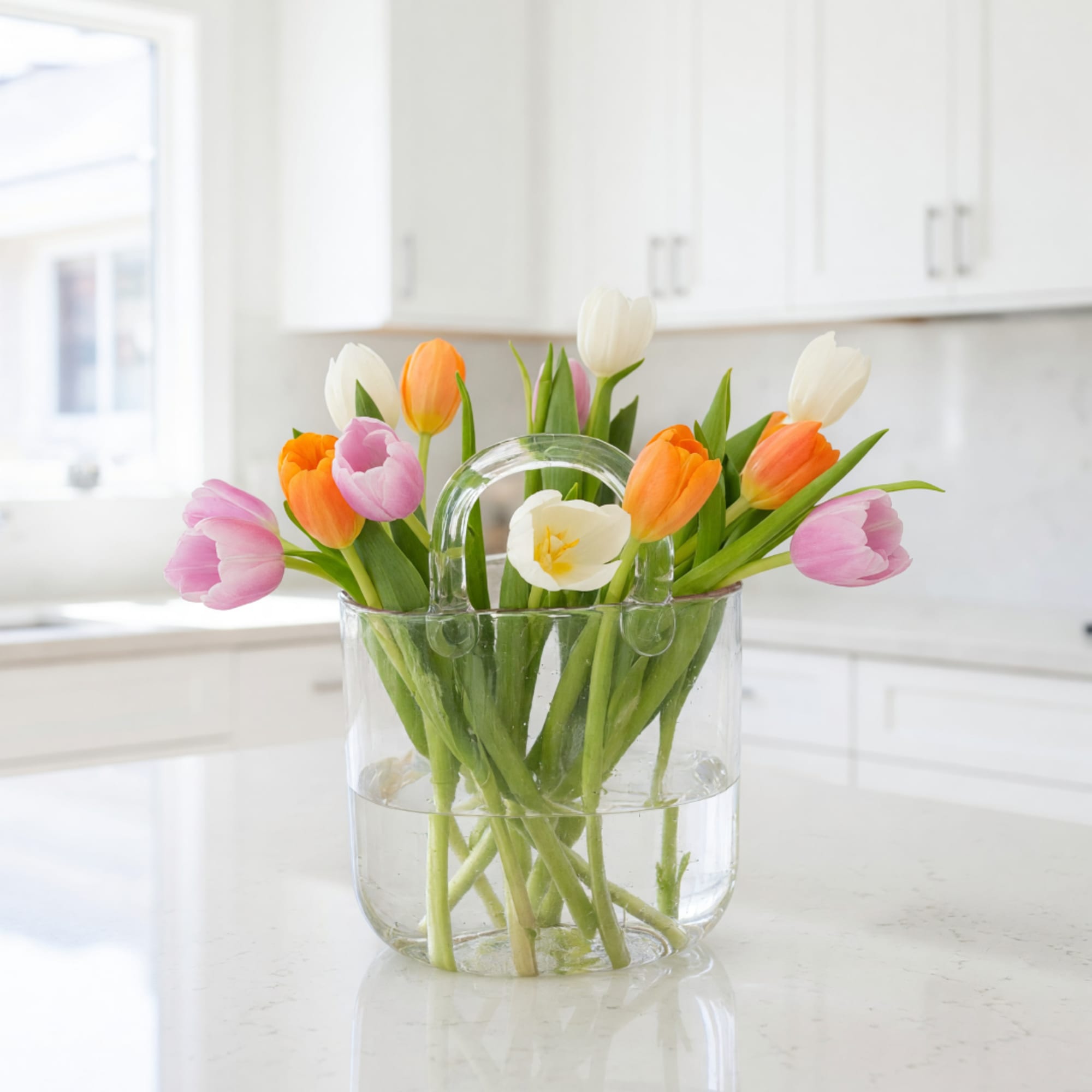 Colorful tulips arranged in a clear glass vase on a kitchen counter.