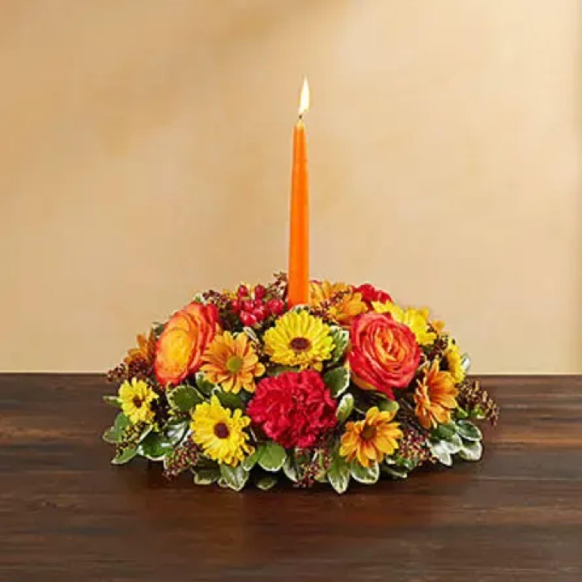 Low floral centerpiece with an orange candle in the middle