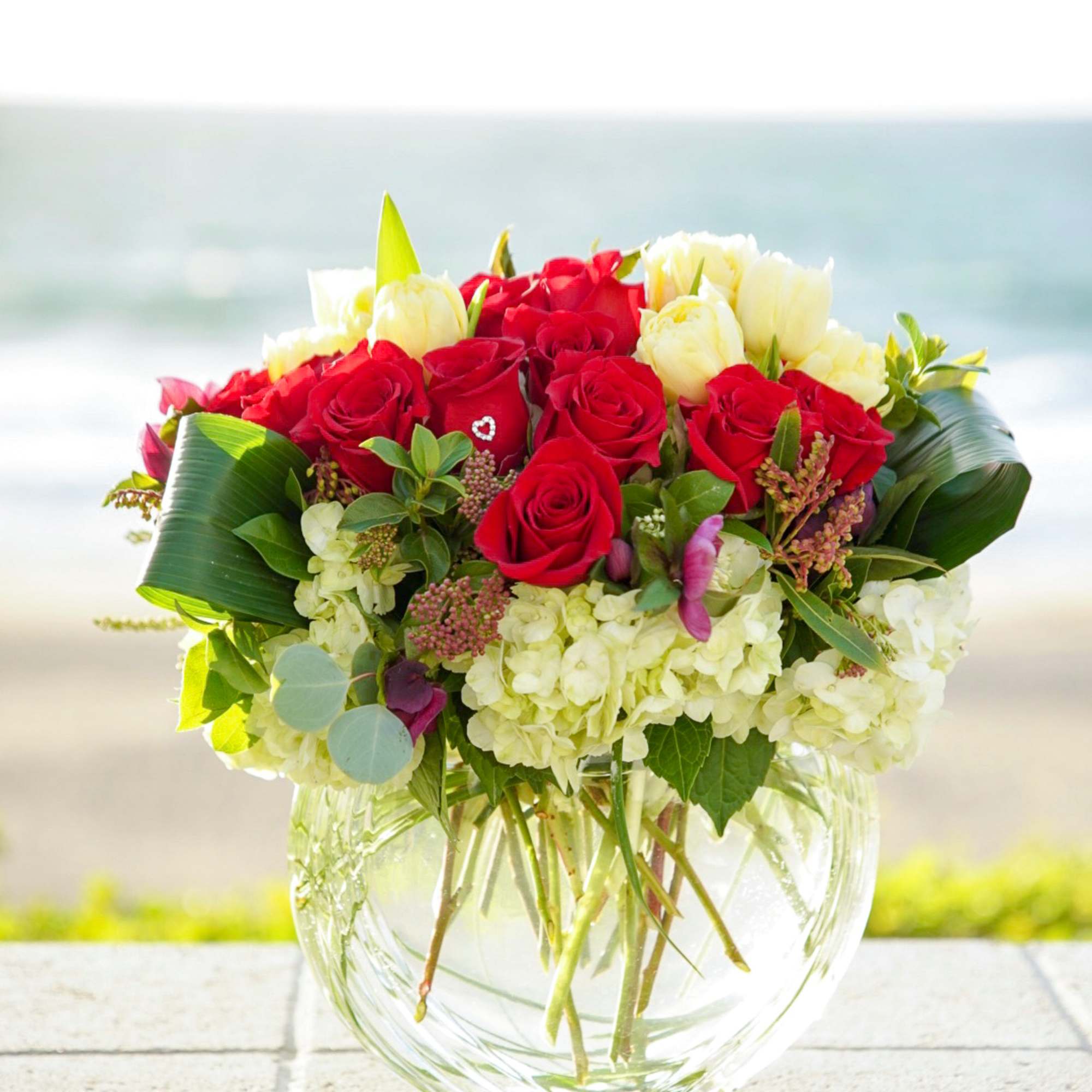 Red and white rose bouquet in a clear glass vase
