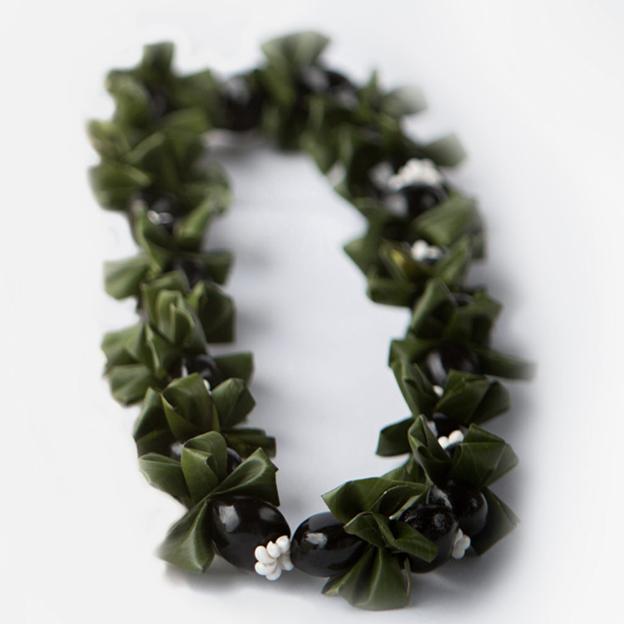 Green leaf lei with black bead accents on a white background