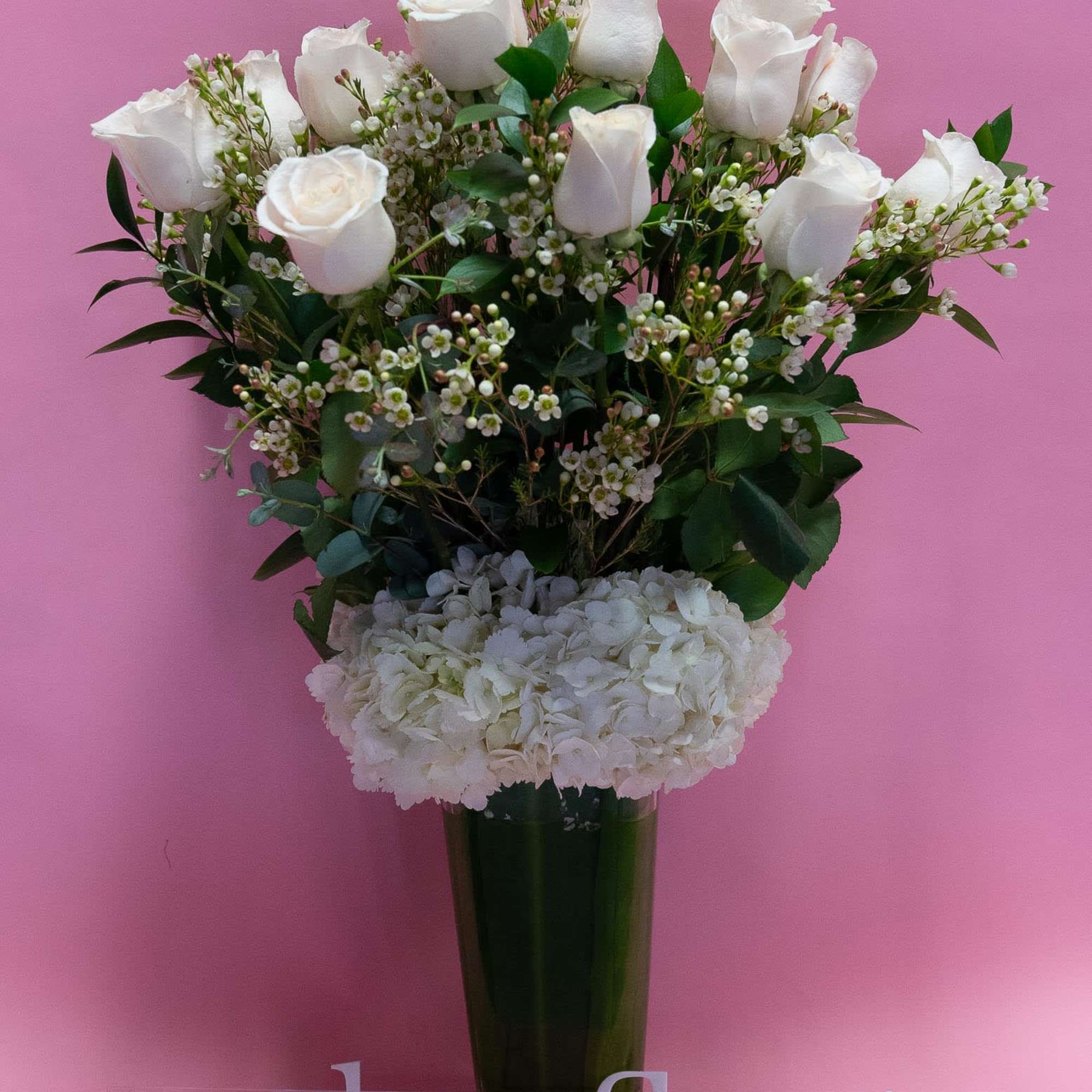 White roses and hydrangeas in a tall glass vase