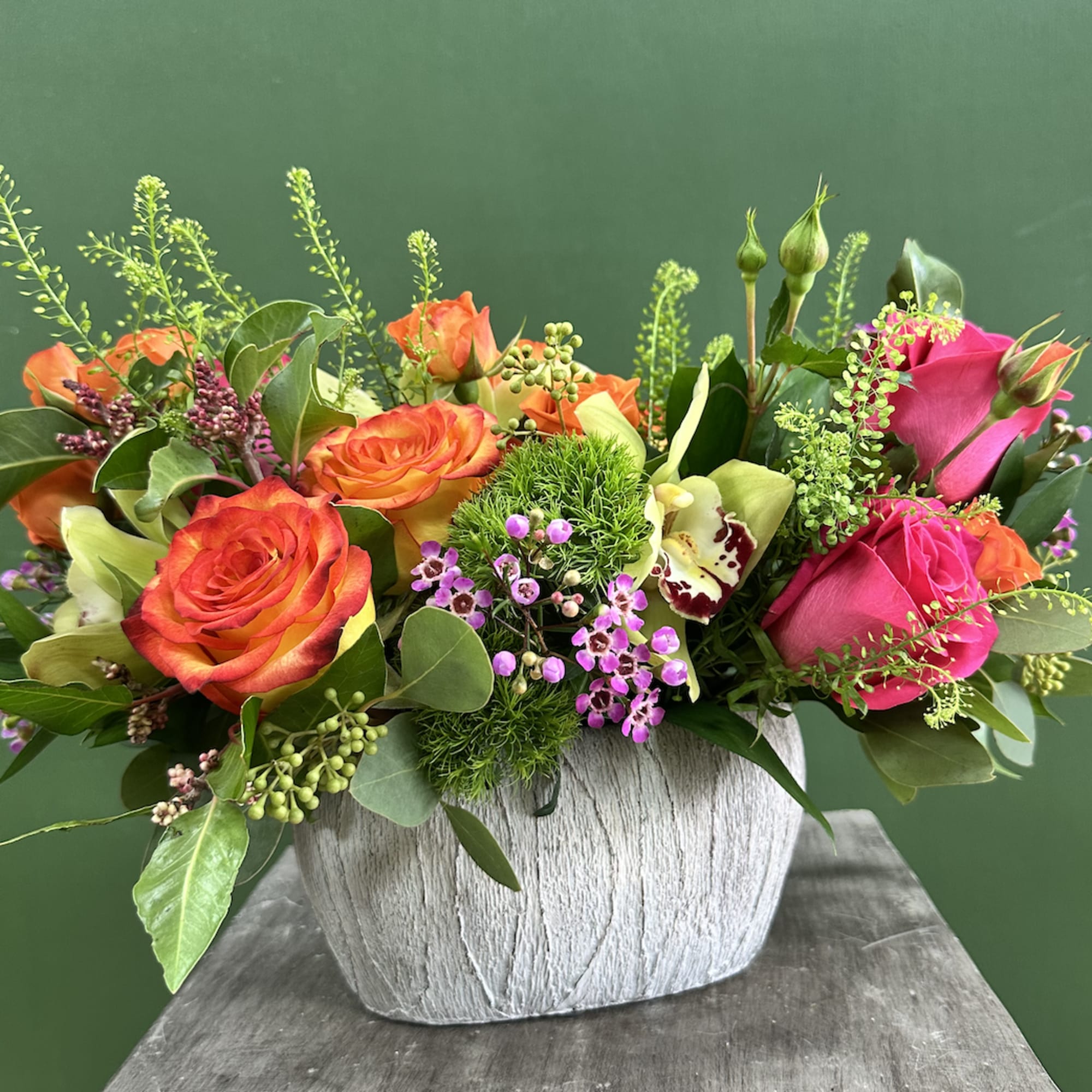 Bright mixed bouquet of orange and pink roses in a gray vase