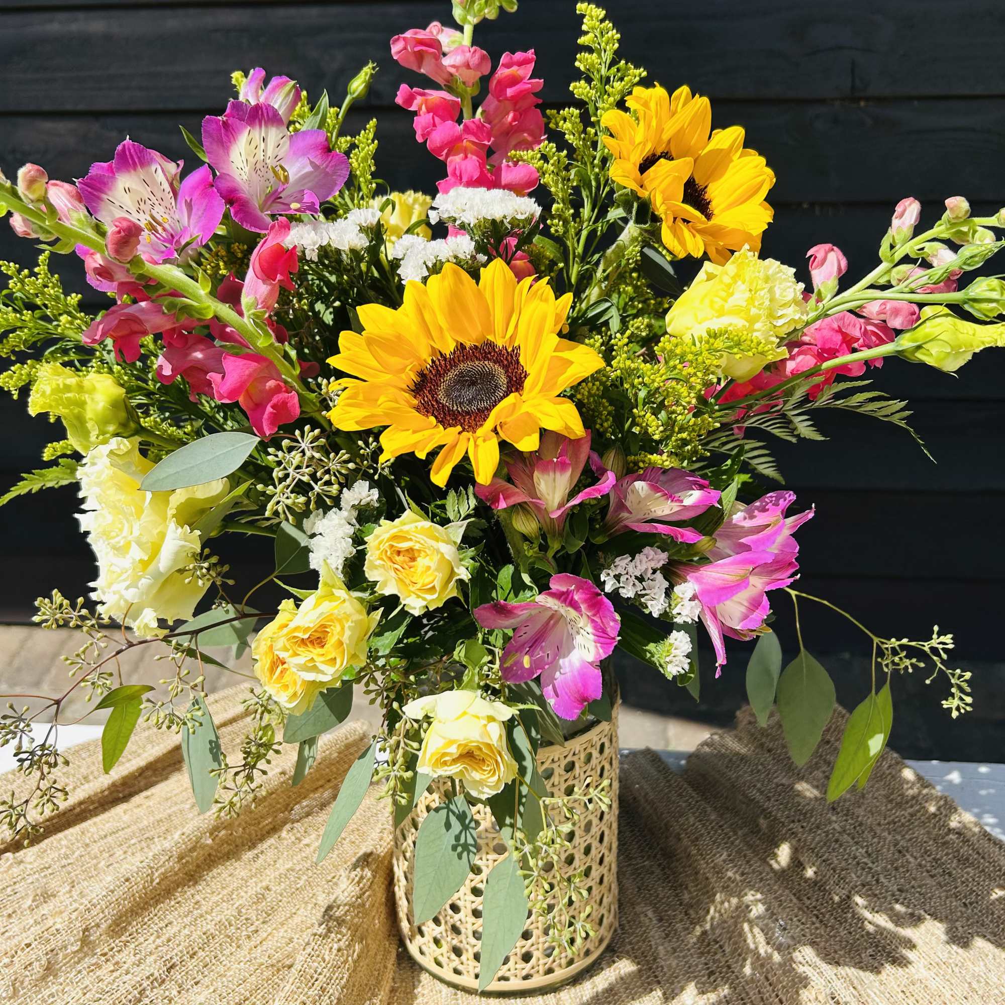 Mixed bouquet with sunflowers, pink alstroemeria, and yellow roses in a decorative vase