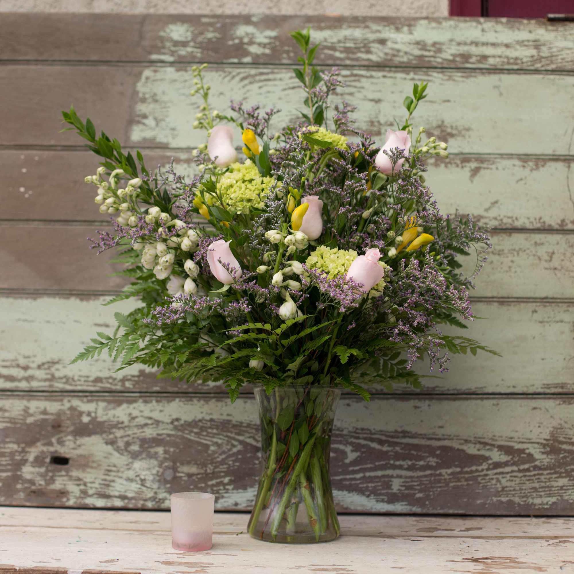 Mixed bouquet in a clear glass vase with pink and yellow blooms