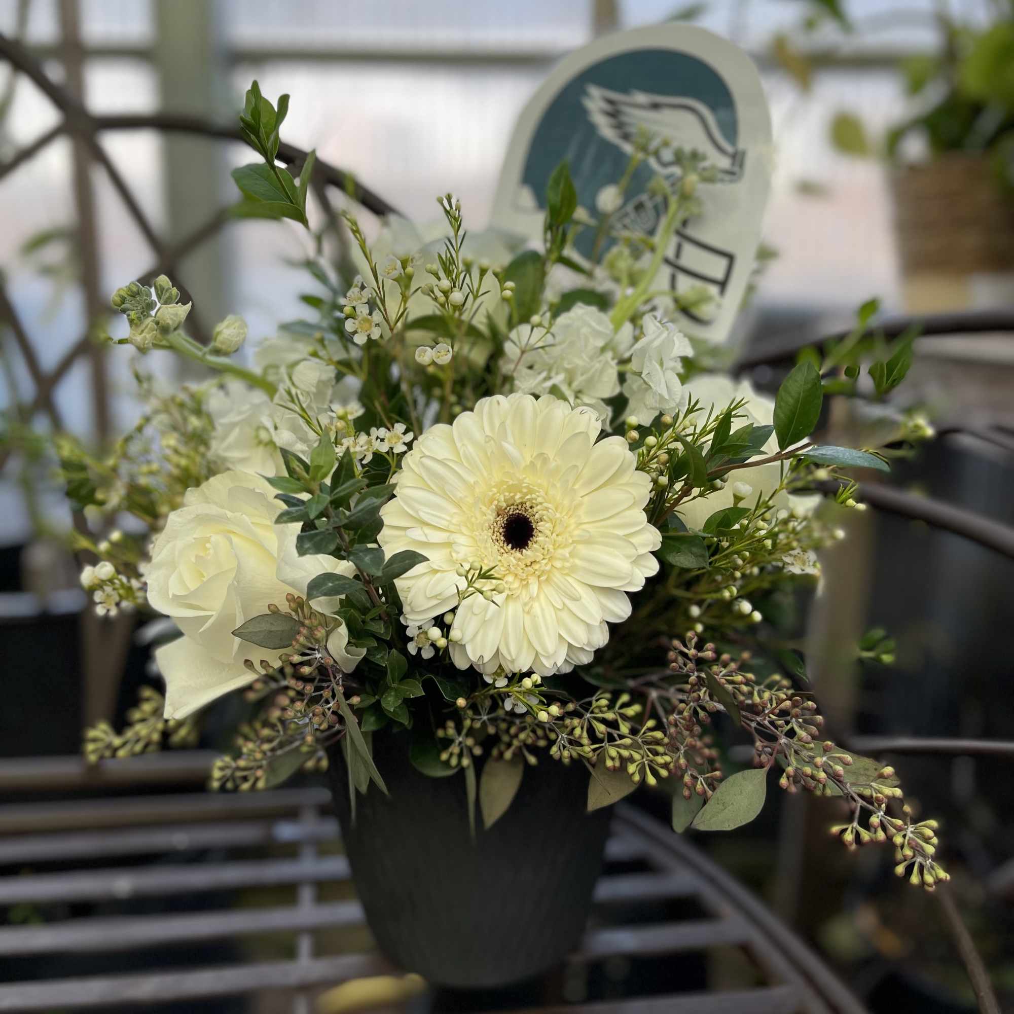 White flowers arranged in a black pot with greenery