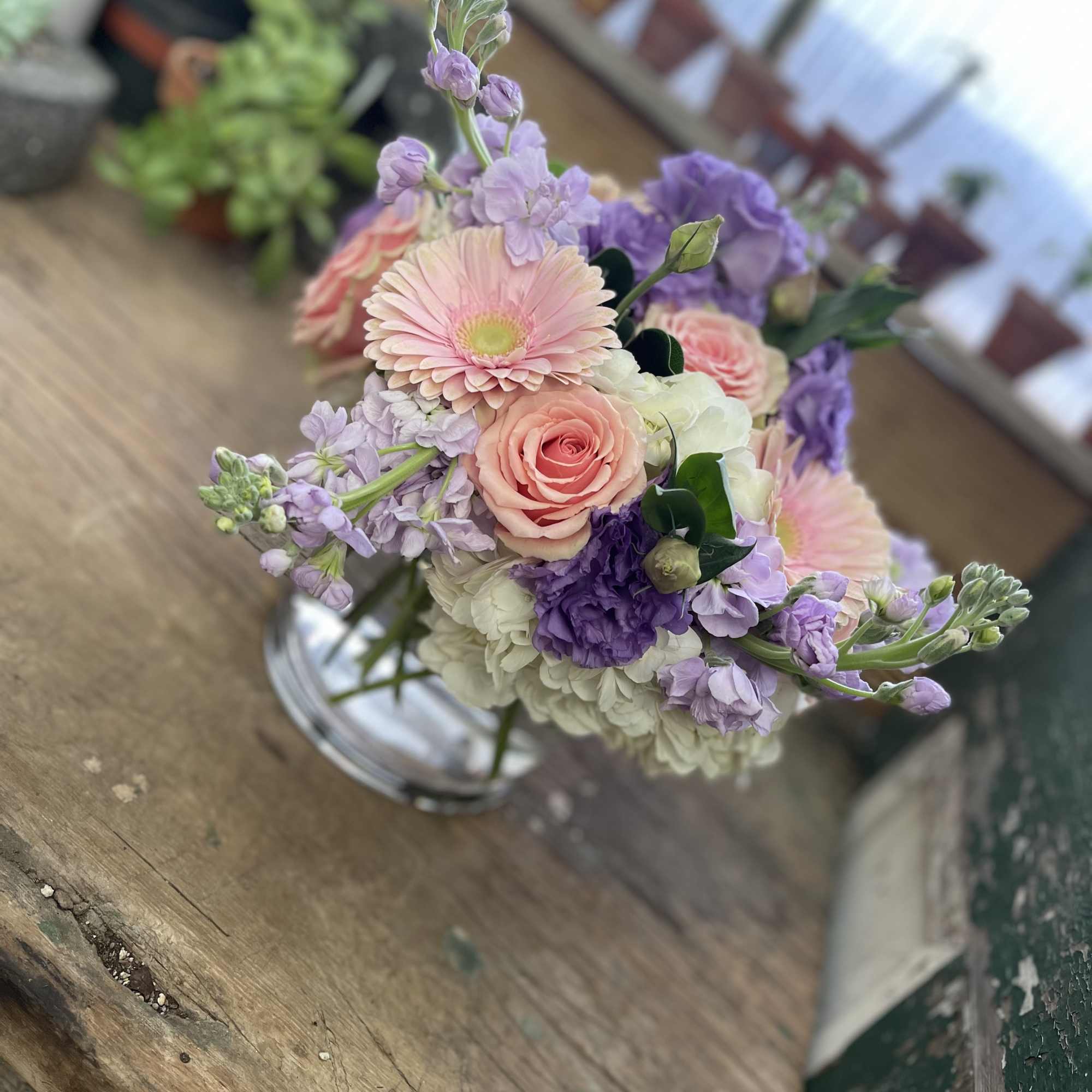 Pastel bouquet of pink, purple, and white flowers in a clear glass vase